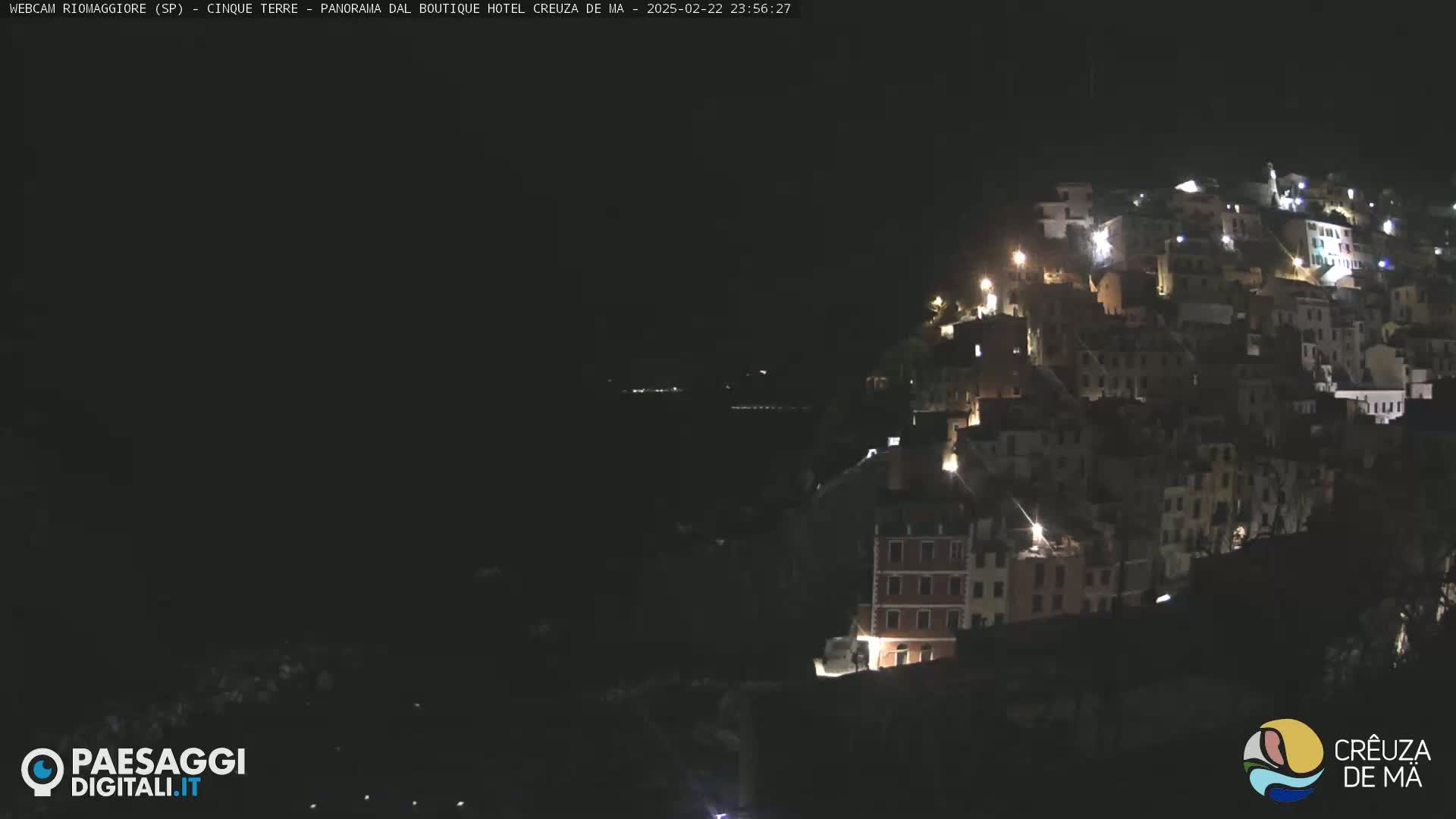 A hillside town is illuminated at night under a dark, clear sky.