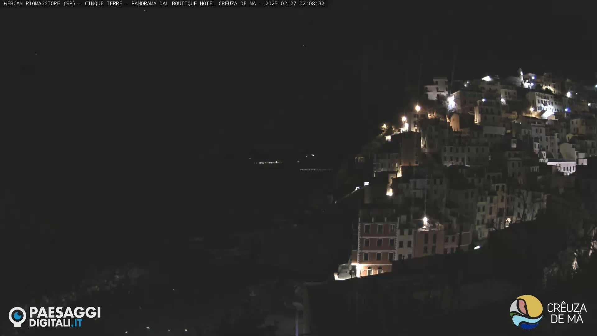 A hillside town is illuminated at night under a clear, dark sky.