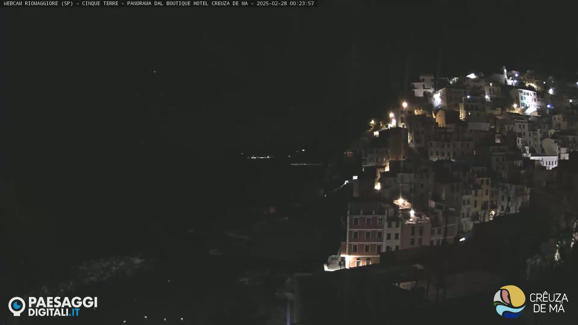 A nighttime view of a hillside village with many lit windows.