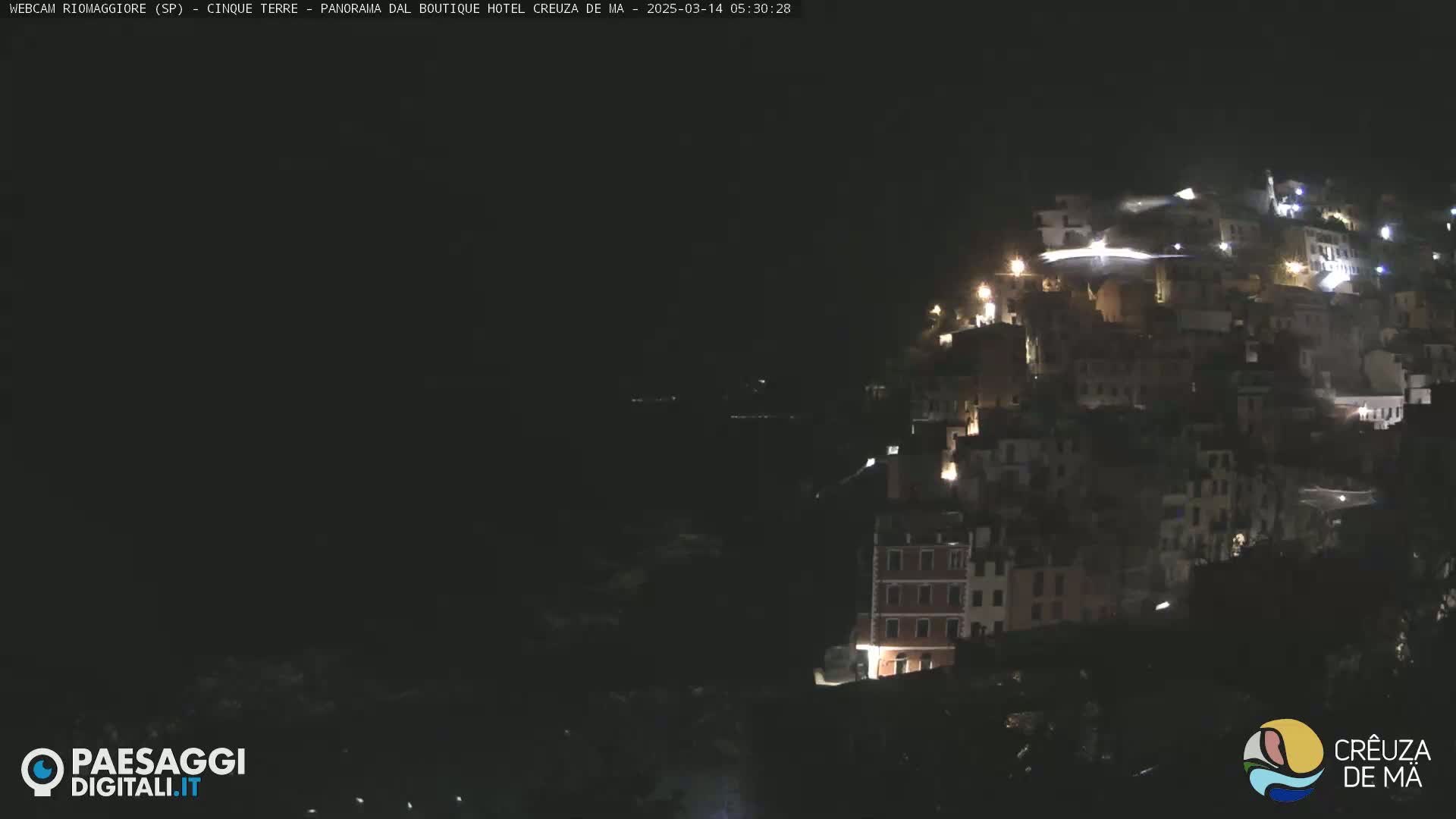 A nighttime view of a hillside town illuminated by scattered lights.
