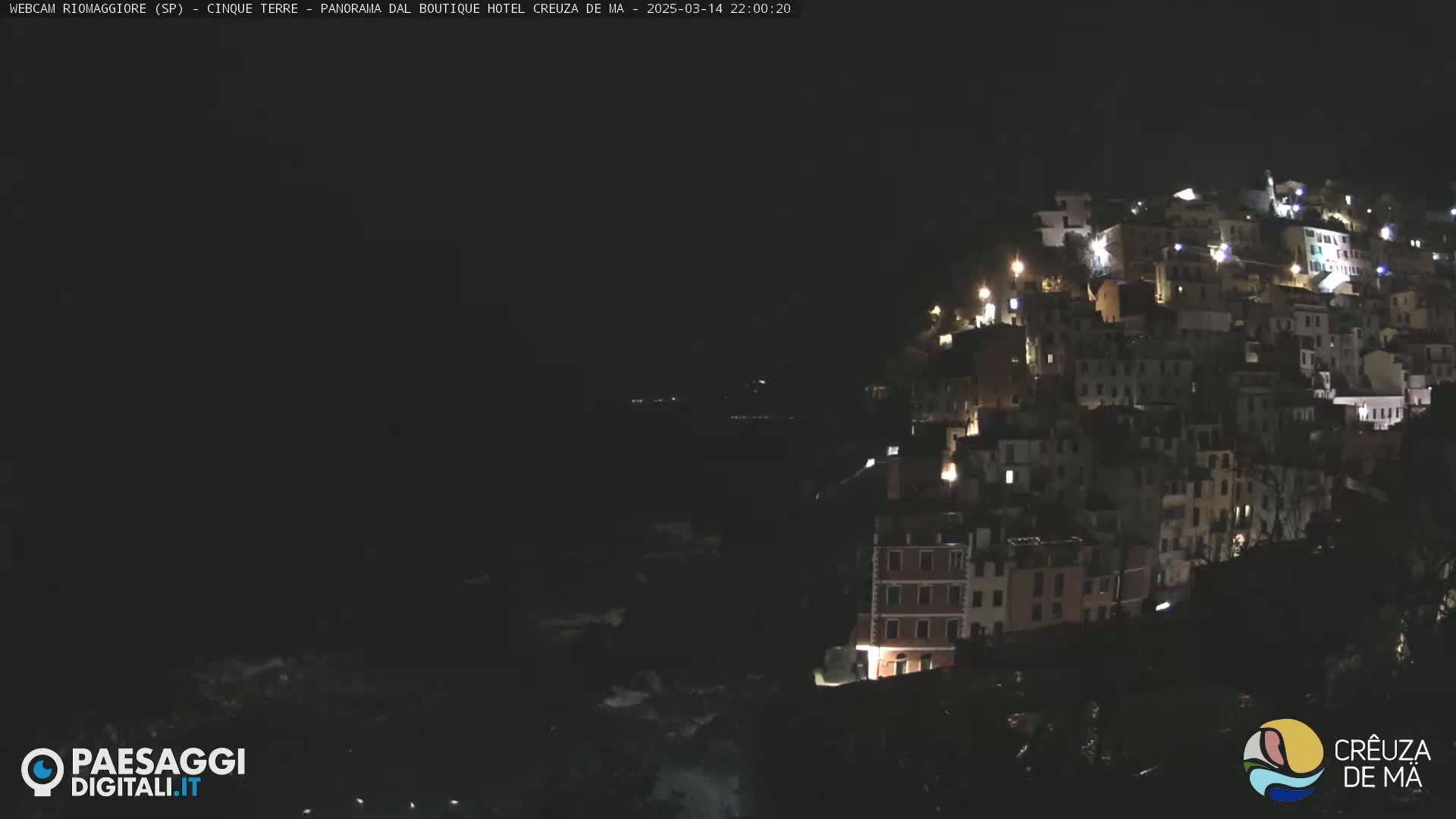 A nighttime view of a hillside village with many buildings illuminated by lights.