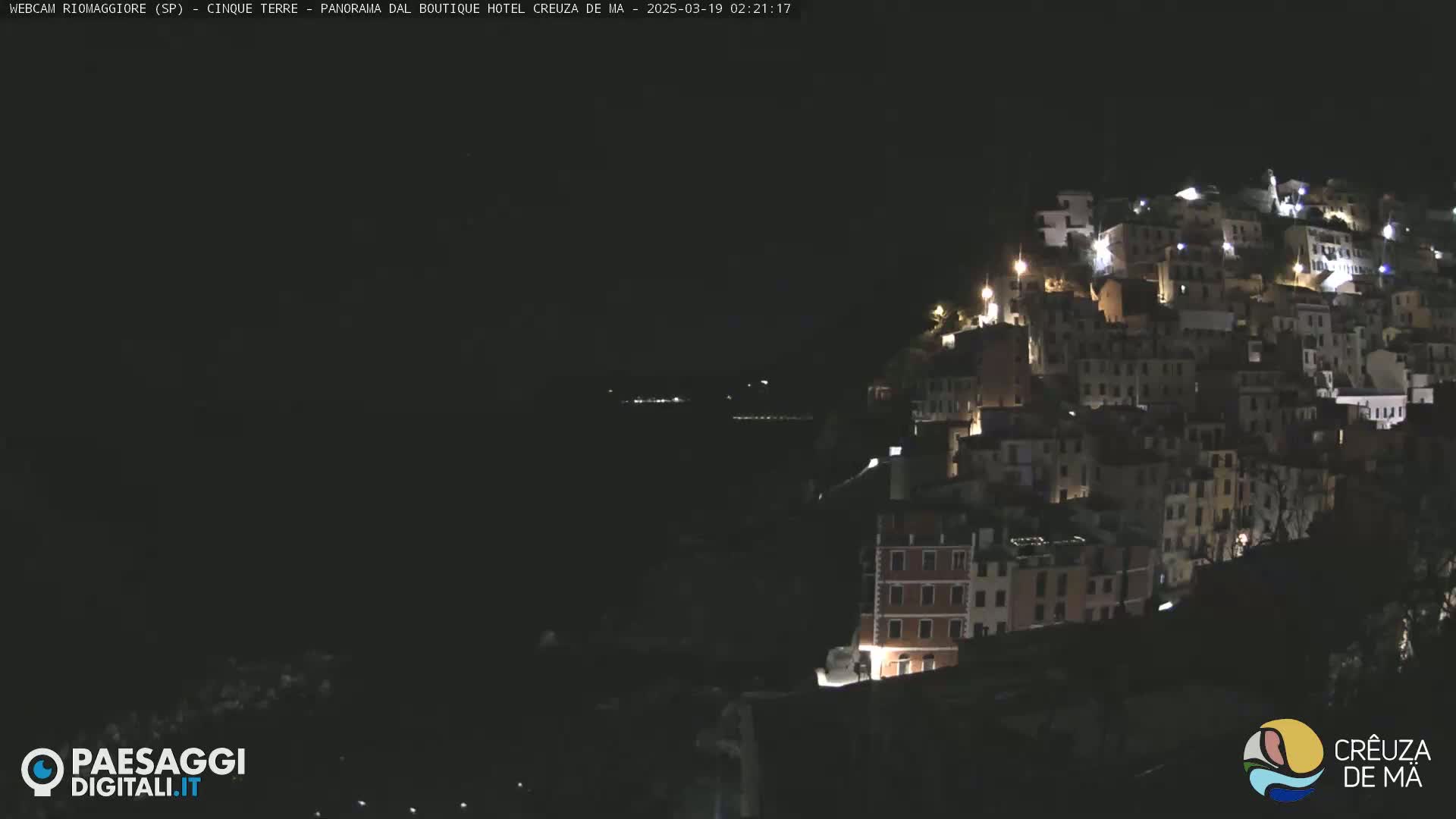 A nighttime view of a hilltop village with many buildings illuminated by lights.