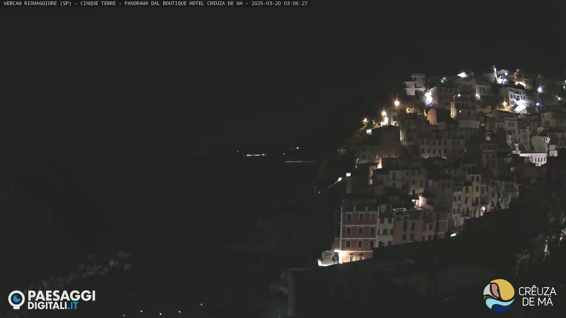 A nighttime view of a hillside village illuminated by scattered lights.