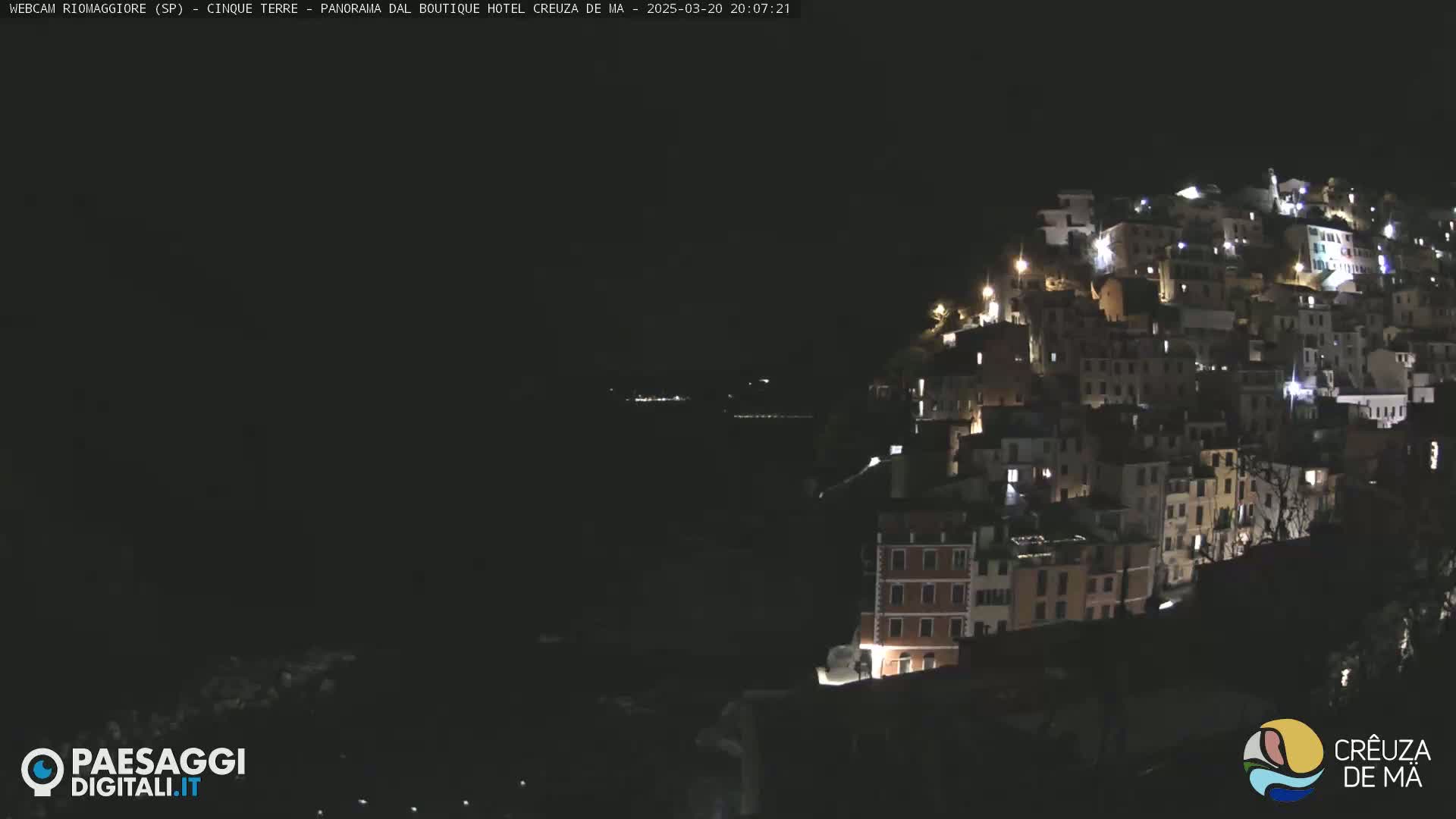 A nighttime view of a hillside village with many illuminated buildings.