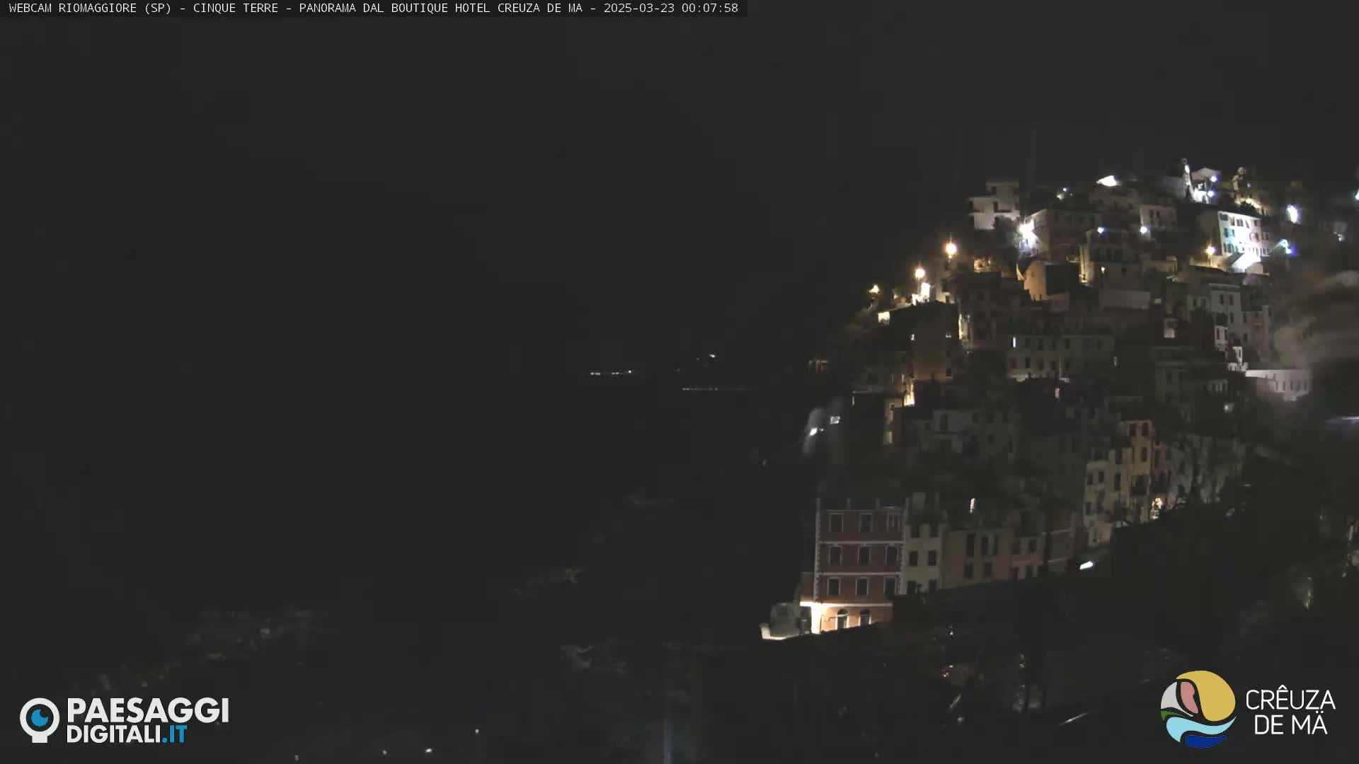 A hillside village is illuminated at night.