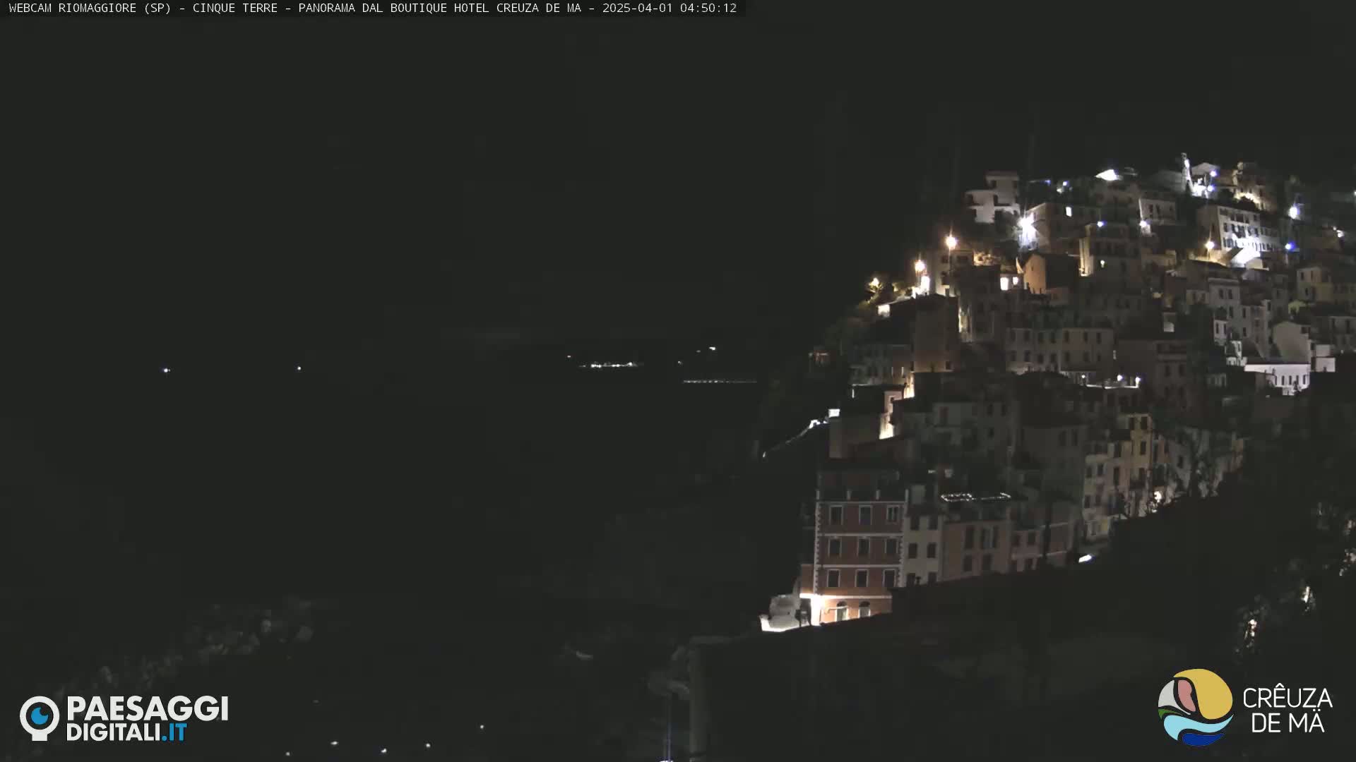 A hillside town is illuminated at night under a dark sky.