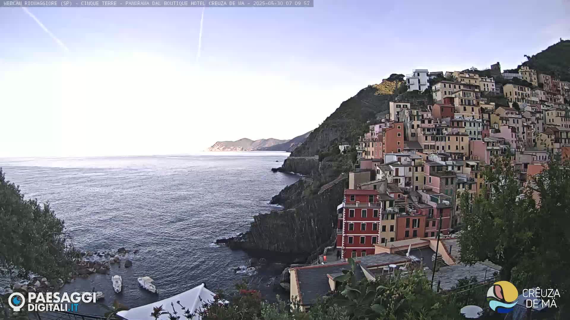 A coastal town with colorful buildings perched on a steep cliff overlooking a calm sea under a clear sky.