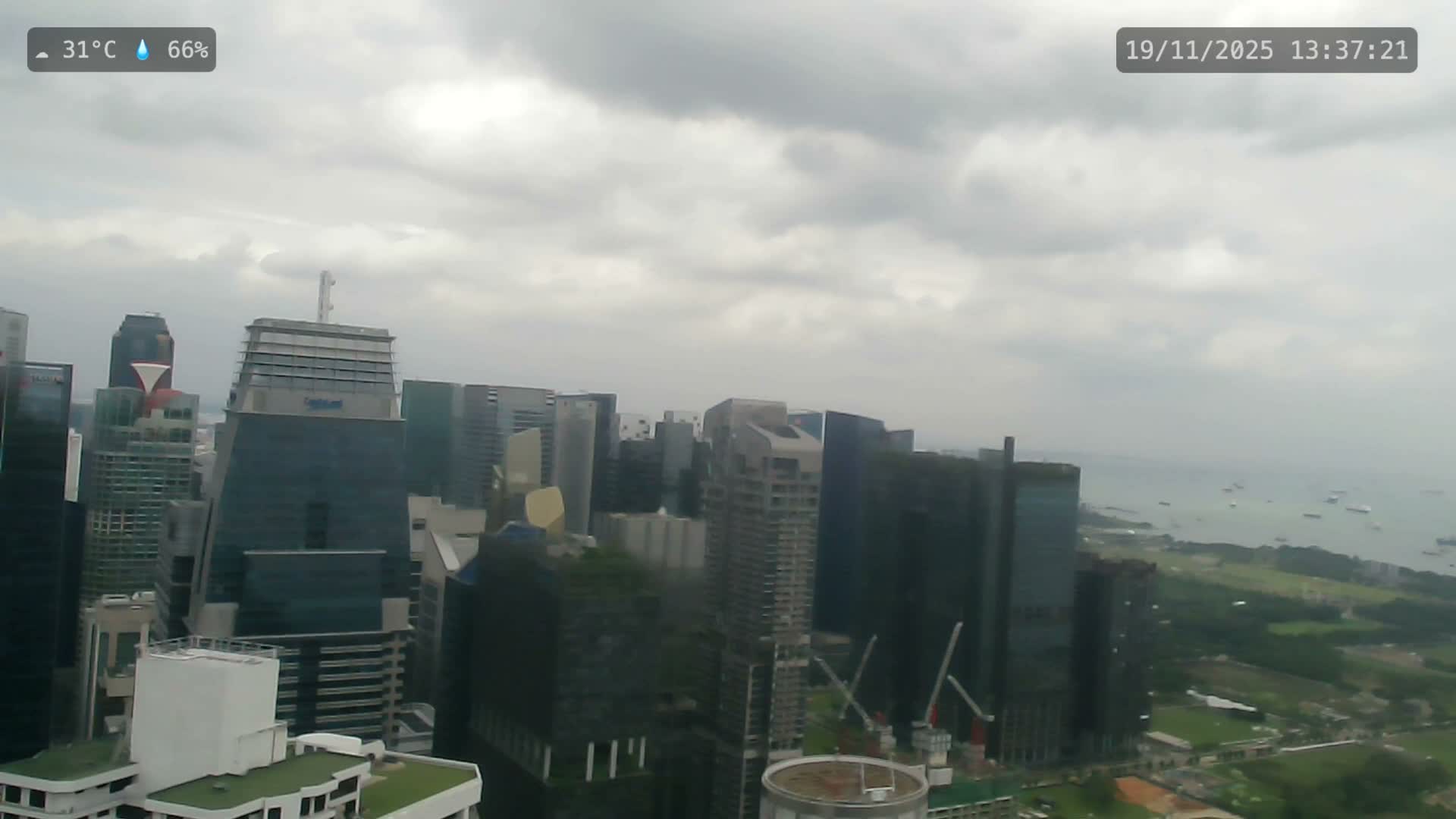 An expansive cityscape featuring numerous modern skyscrapers is visible under a heavily overcast, gray, and hazy sky, suggesting damp weather conditions.