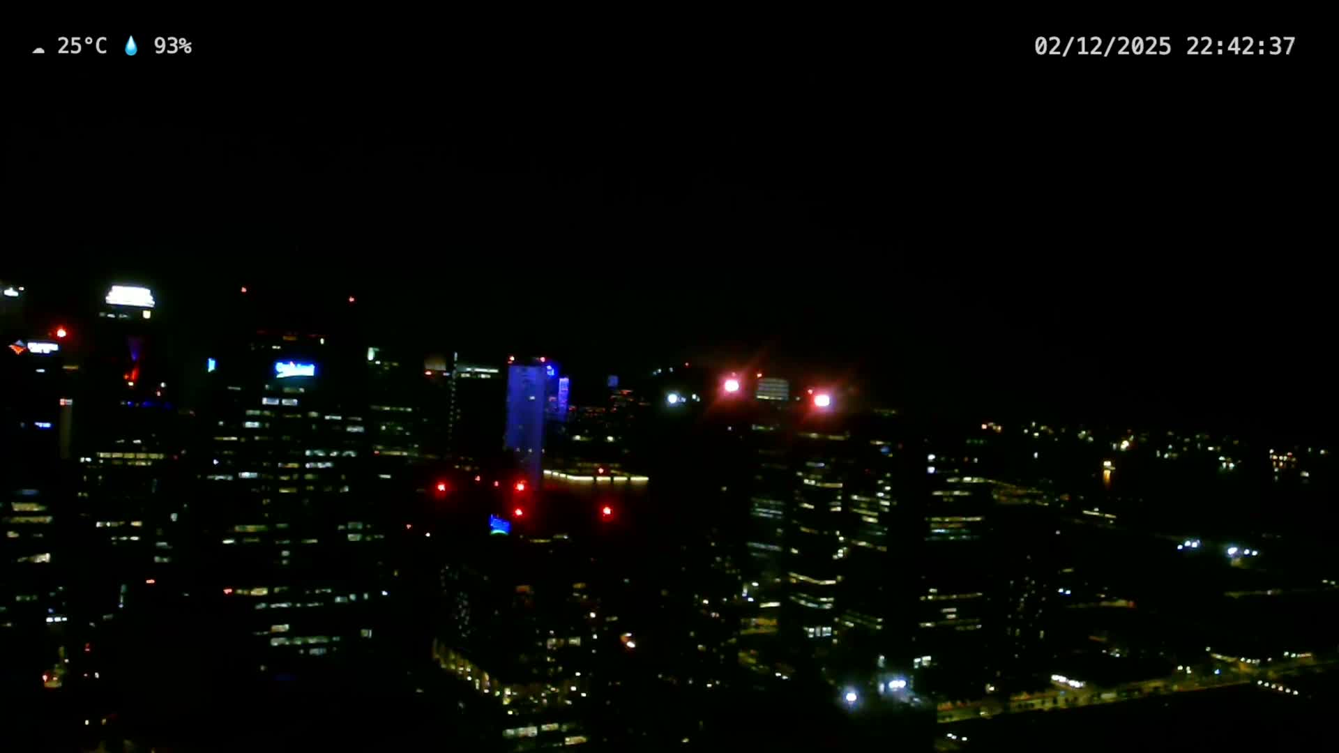 An expansive night cityscape is illuminated by countless lights from buildings and streets under a clear dark sky.