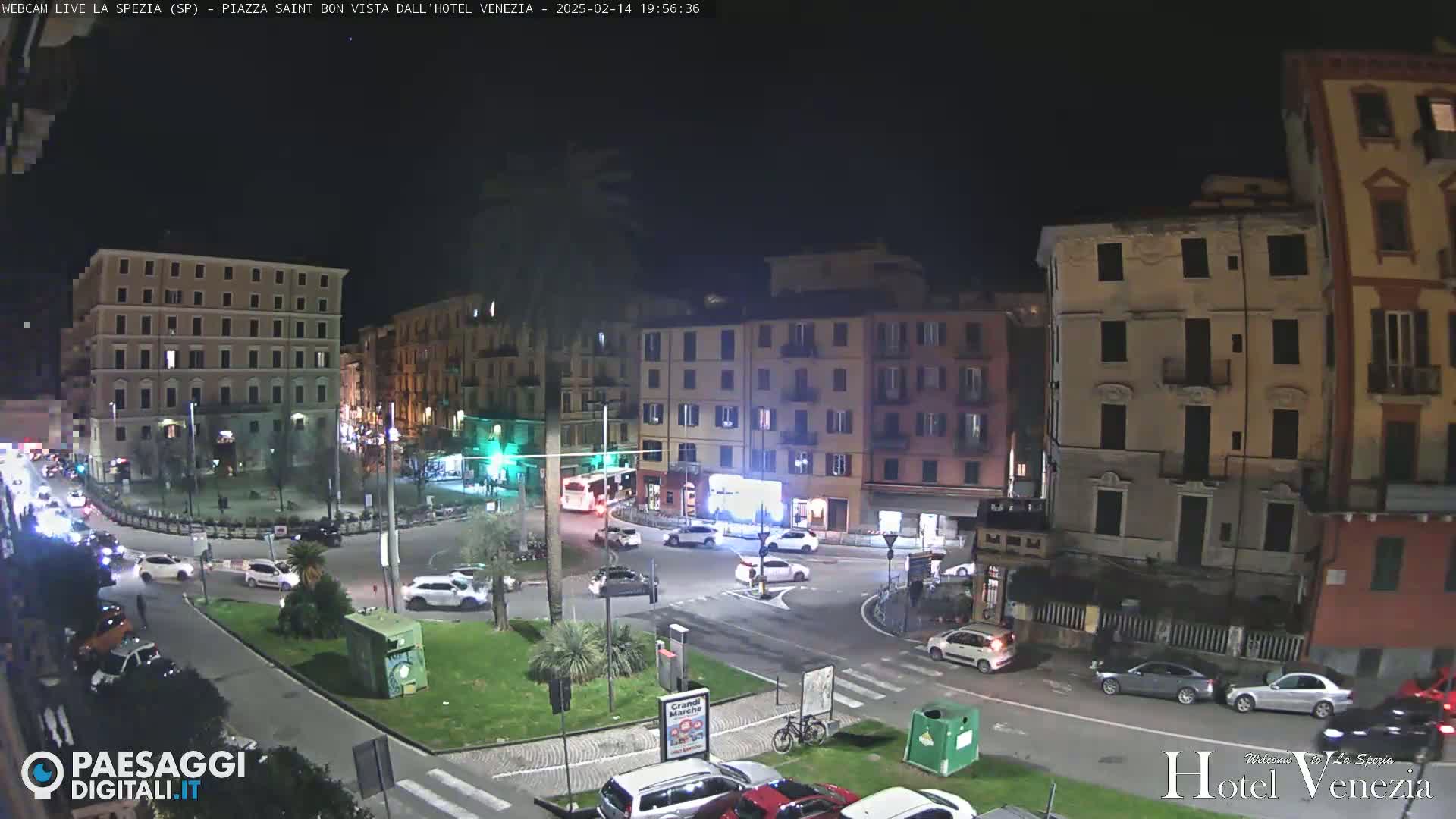 A nighttime view of a city square with cars and buildings under clear skies.