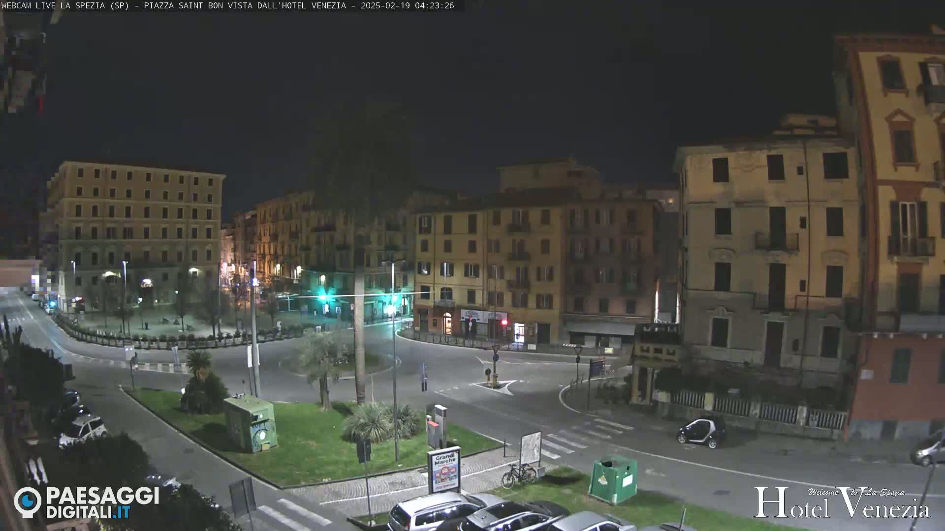 A nighttime, mostly empty city square surrounded by multi-story buildings.