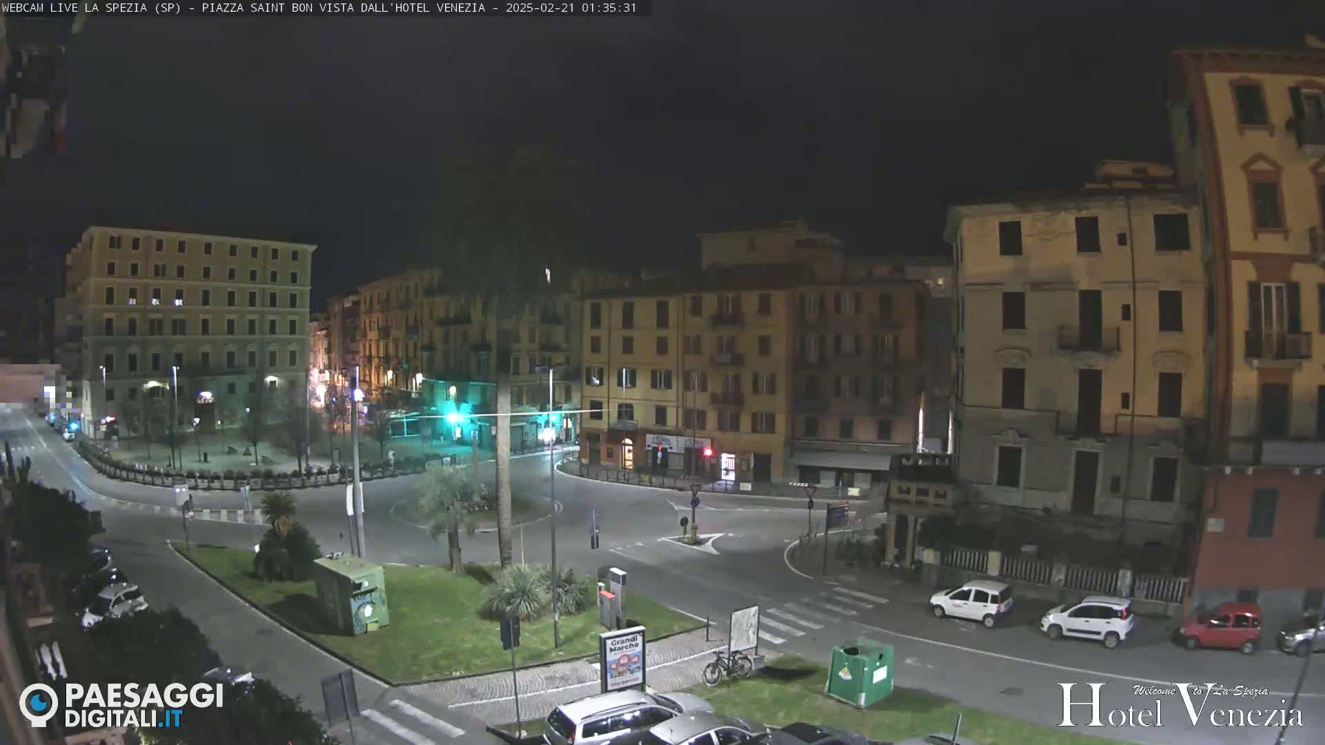 A nighttime view of a mostly empty plaza surrounded by multi-story buildings.