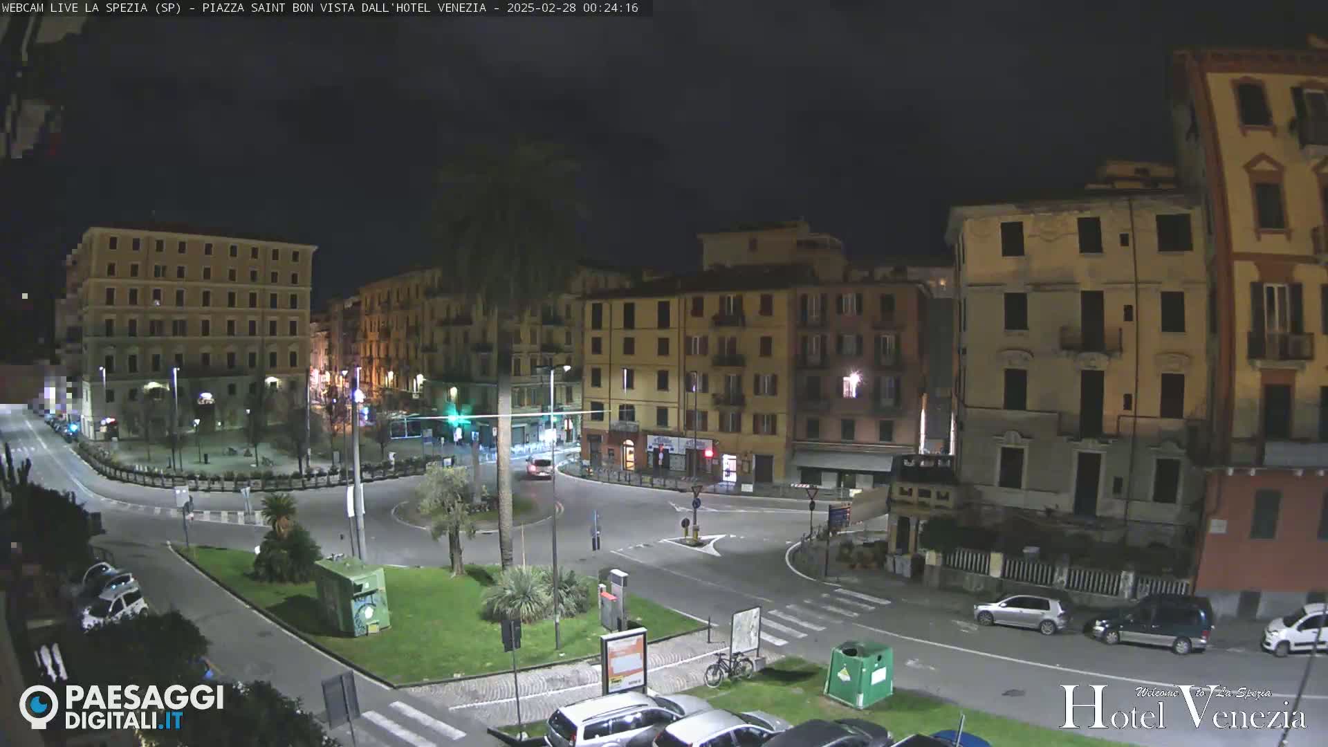 A nighttime view of a city square in Italy, with several multi-story buildings surrounding a roundabout.