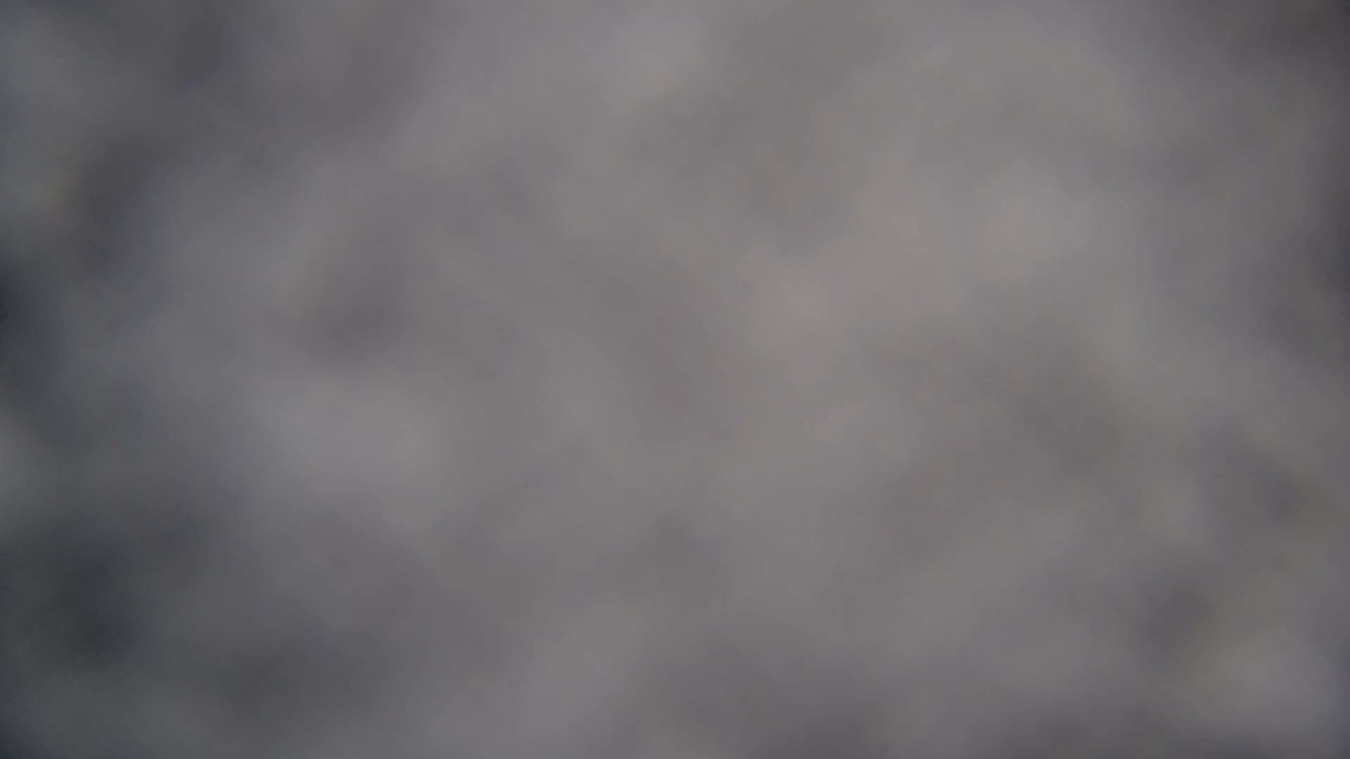 Empty ski lift chairs, some lightly frosted, disappear into a thick, gray fog, indicating extremely low visibility and cold, overcast weather.