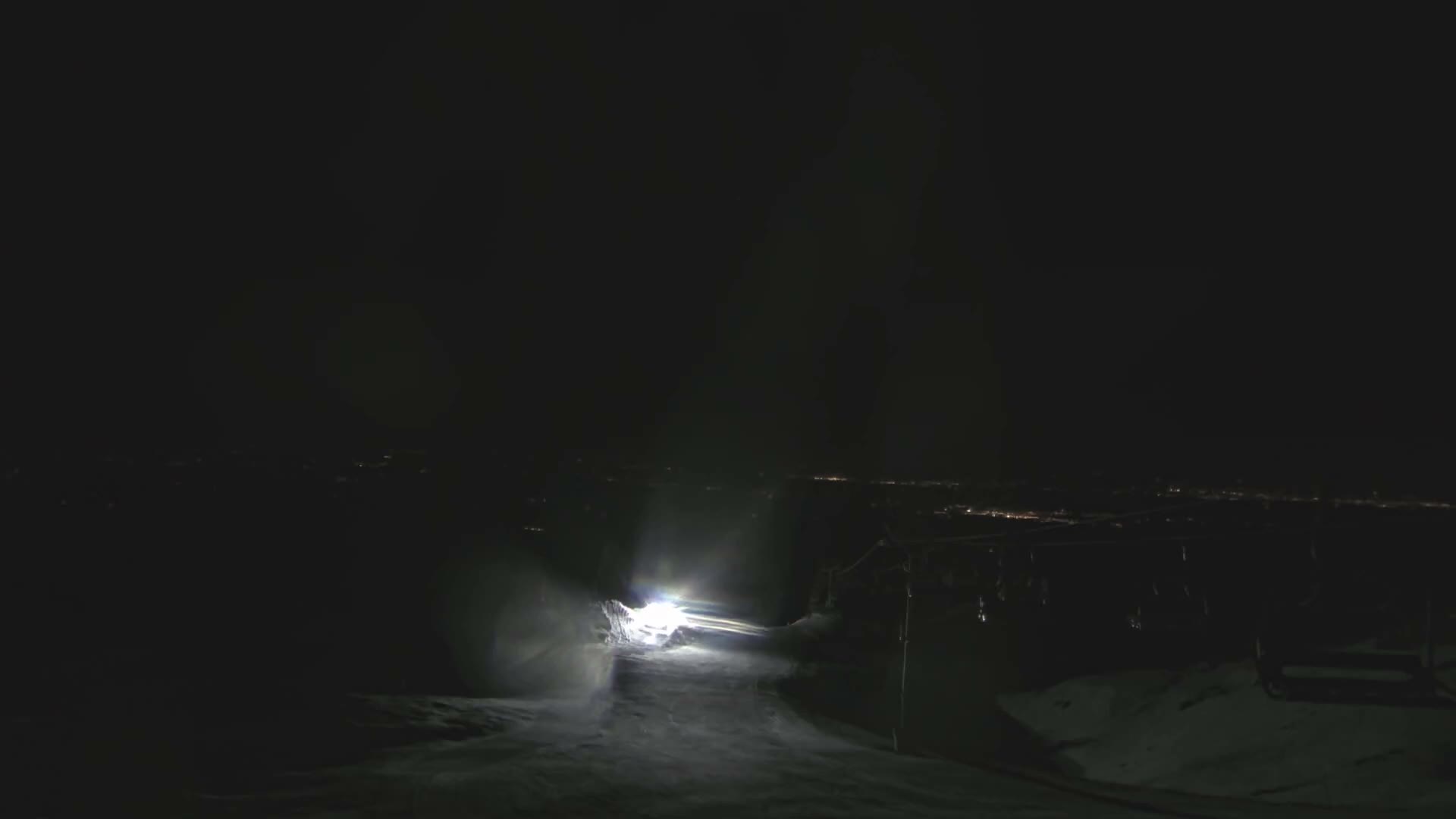 Several empty chairlift chairs and a support tower are partially visible through extremely dense fog or heavy clouds at a ski resort.