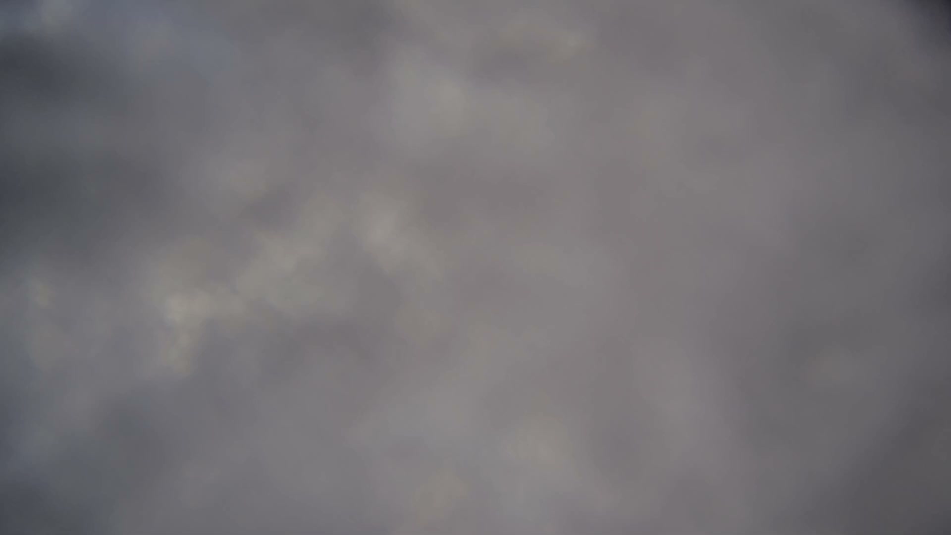 Several empty chairlift chairs and a support tower are partially visible through extremely dense fog or heavy clouds at a ski resort.