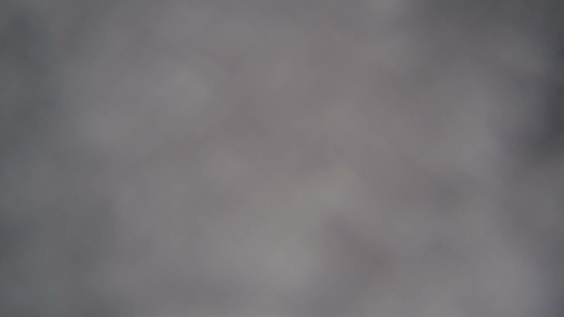 Several empty chairlift chairs and a support tower are partially visible through extremely dense fog or heavy clouds at a ski resort.