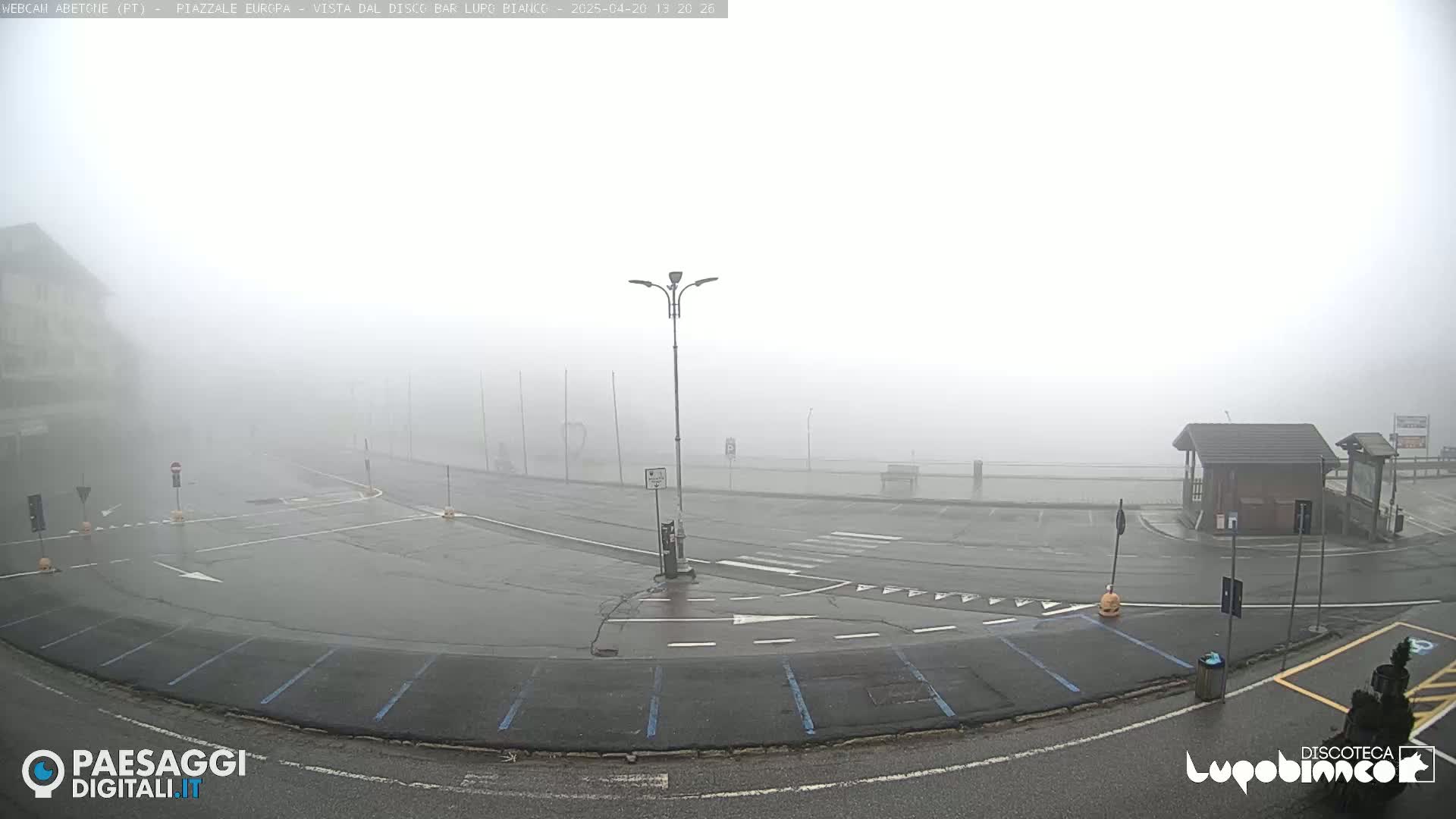 A foggy parking lot with a small building and street lamps is visible.