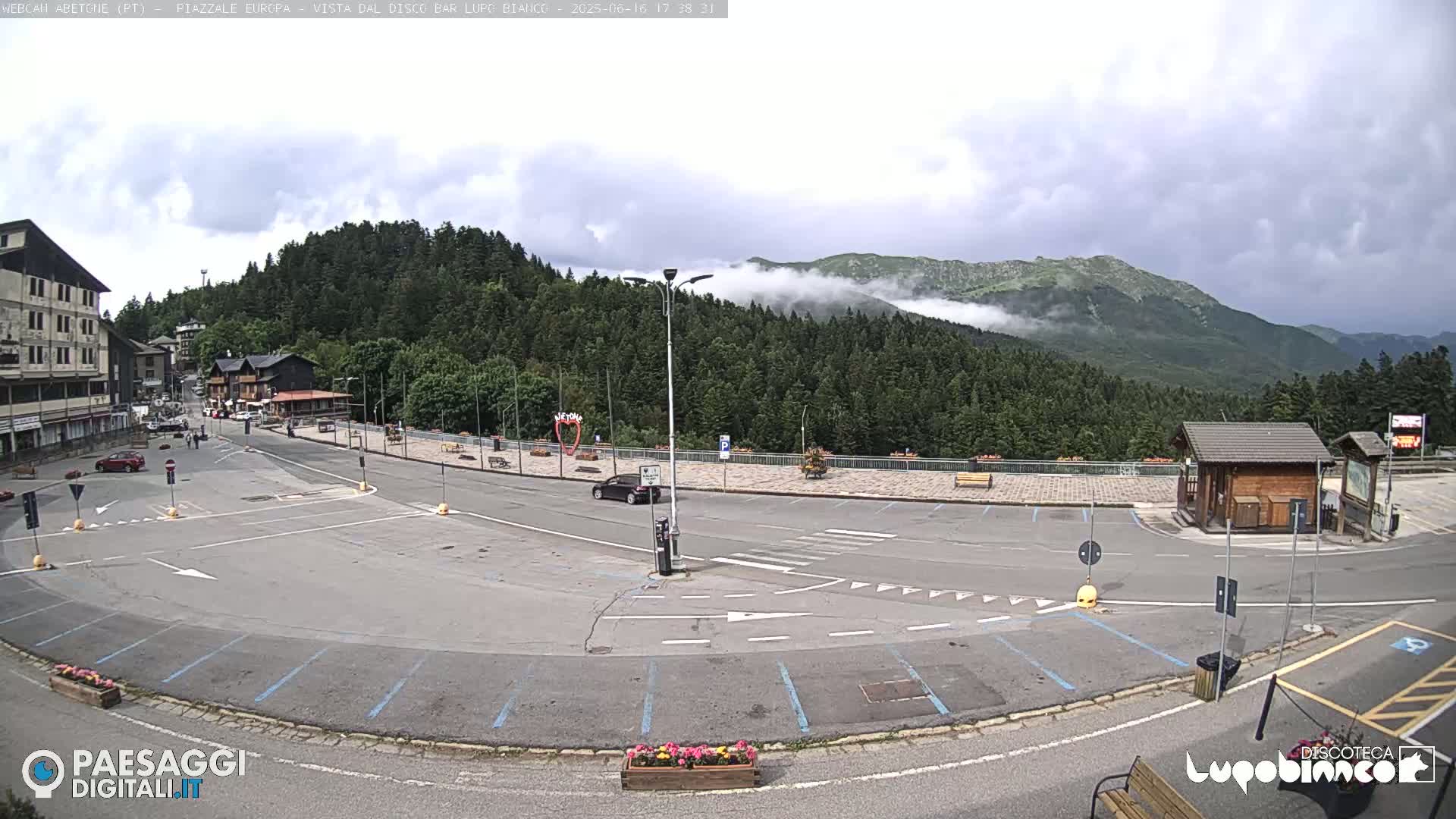 An empty parking lot in a mountainous area with overcast skies and low clouds clinging to the hills.