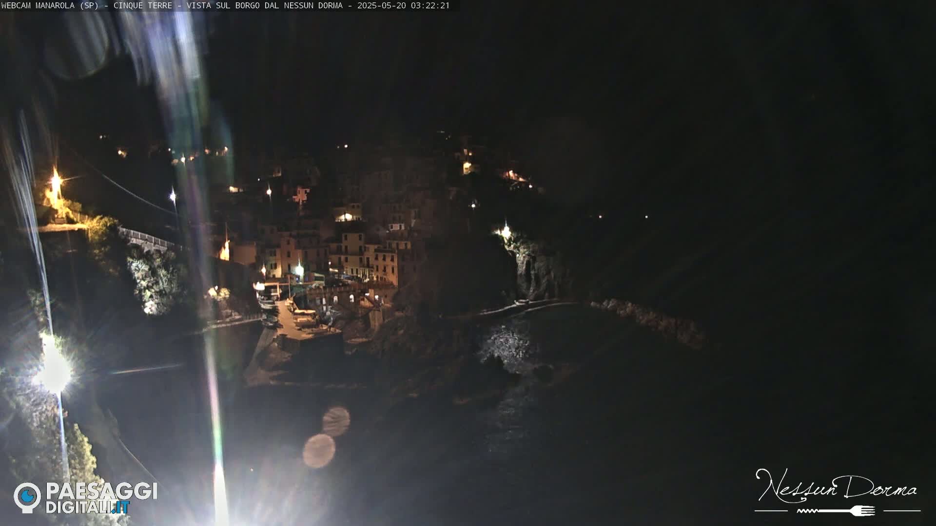 A nighttime view of a coastal town with buildings illuminated against a dark sky.