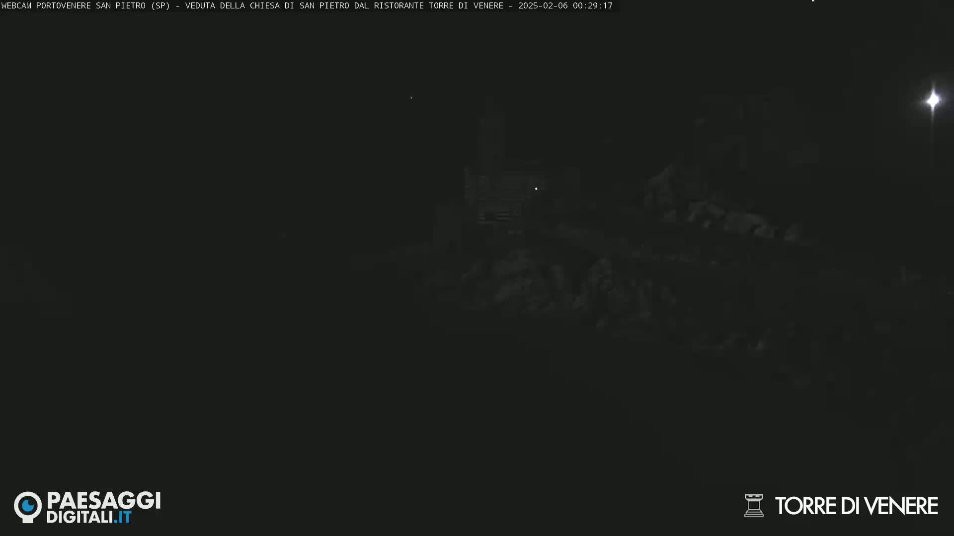 A dark, nighttime scene shows a dimly lit structure and surrounding land.