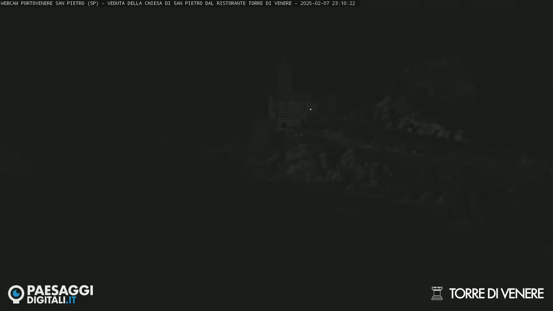 A very dark, nighttime image shows a dimly lit structure in the distance.