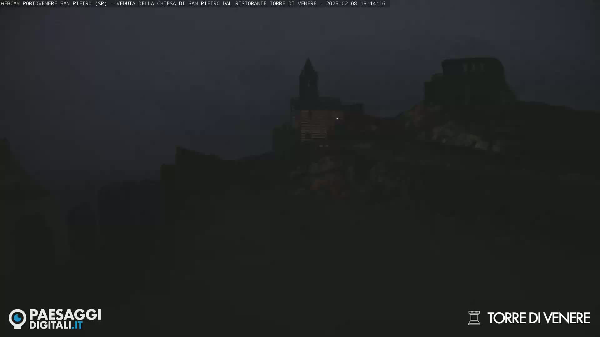 A dark, nighttime view of a village with a church steeple, under a dusky sky.