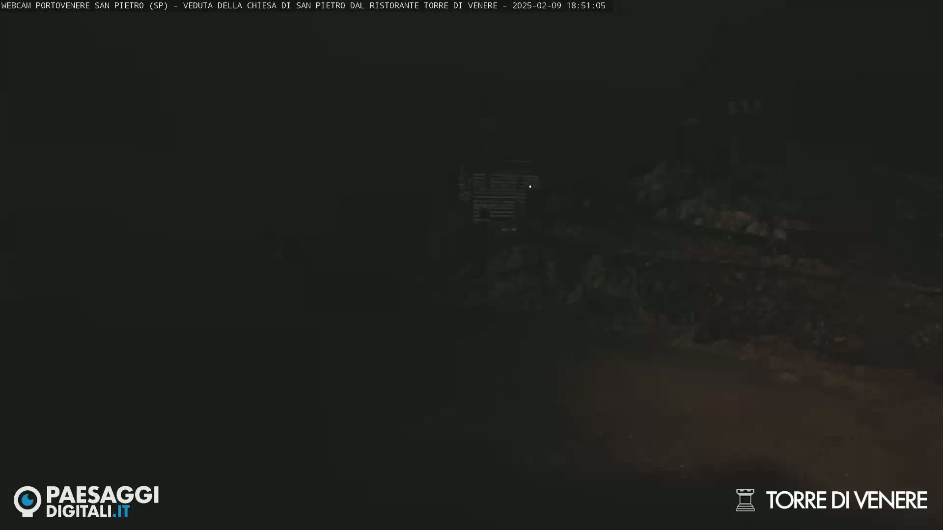 A dark, nighttime scene shows a dimly lit area with indistinct shapes and textures.