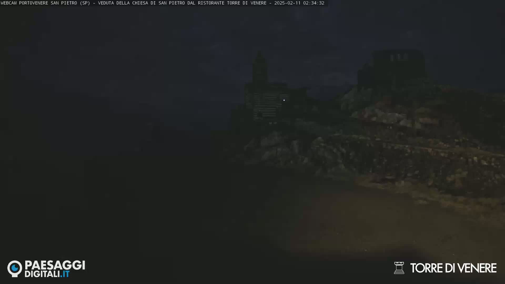 A dark, nighttime view of a stone structure on a rocky outcrop.