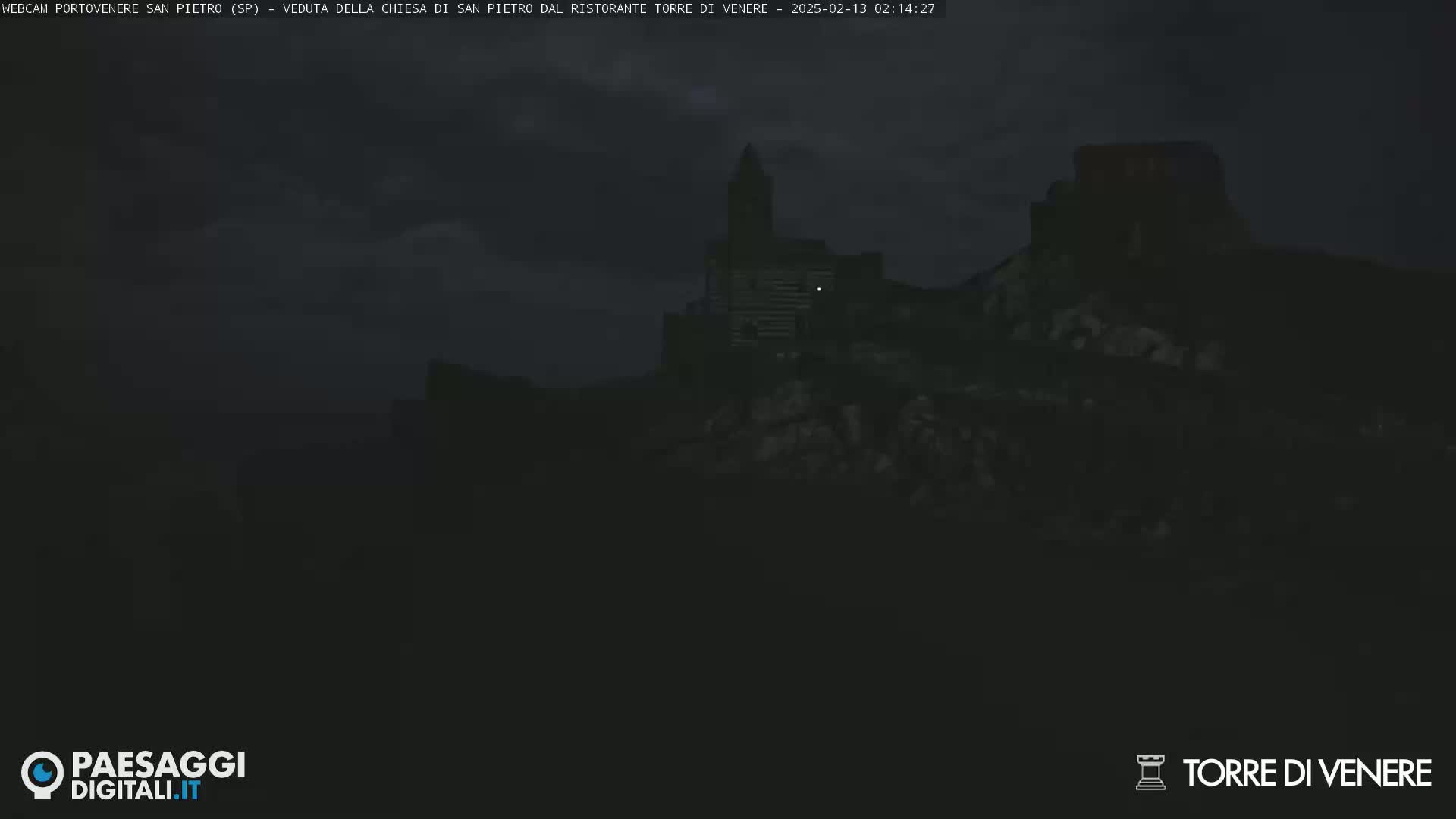 A dark, nighttime view of a stone structure, possibly a church or castle, sits atop a hill under a cloudy sky.