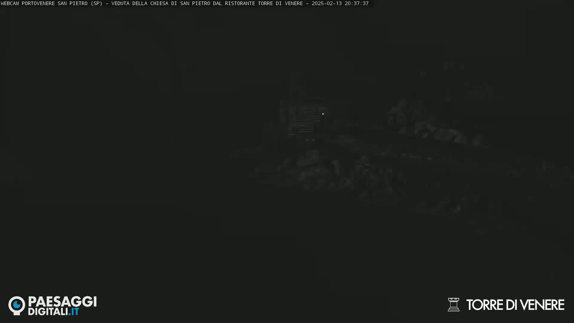 A very dark, nighttime image shows a dimly lit structure and surrounding area.