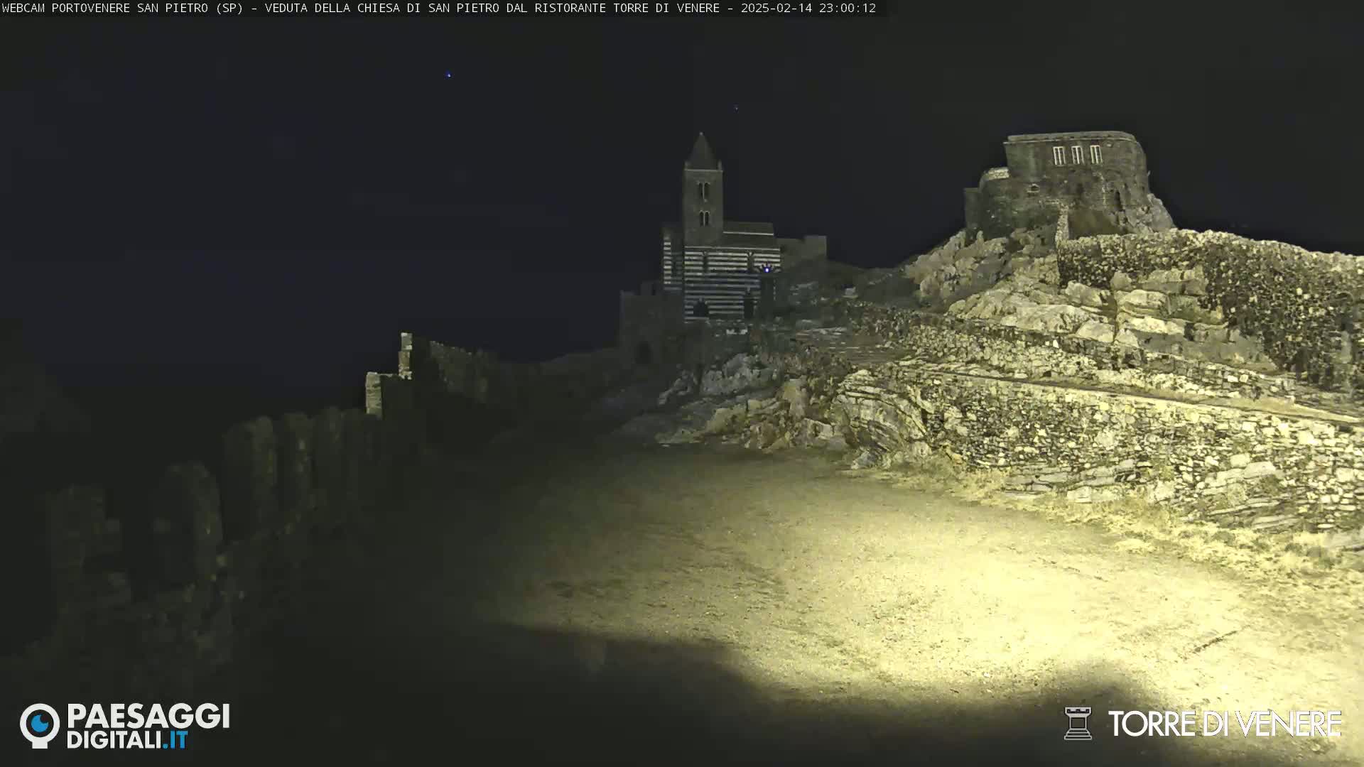 A nighttime view of a stone church and ruins on a rocky hillside under a clear sky.