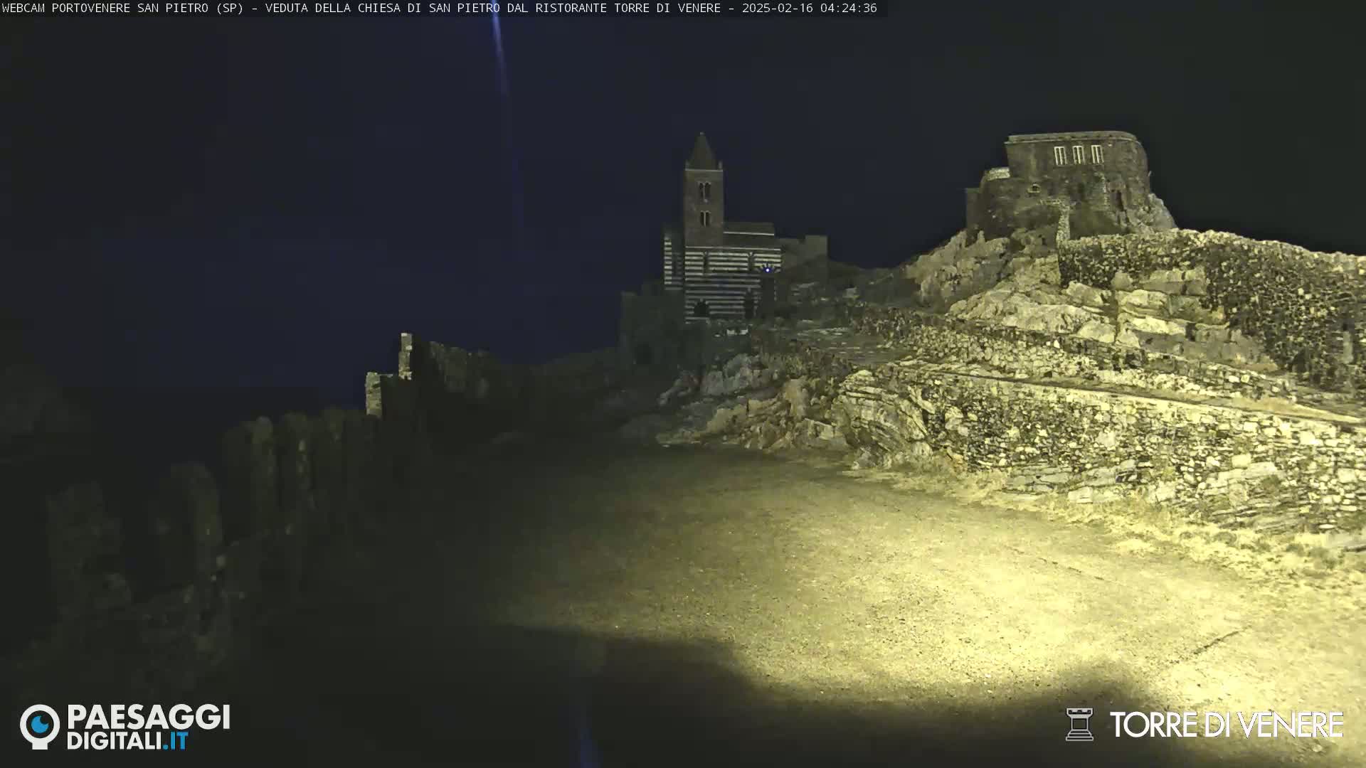A nighttime view of a stone church and ruins illuminated by artificial light.
