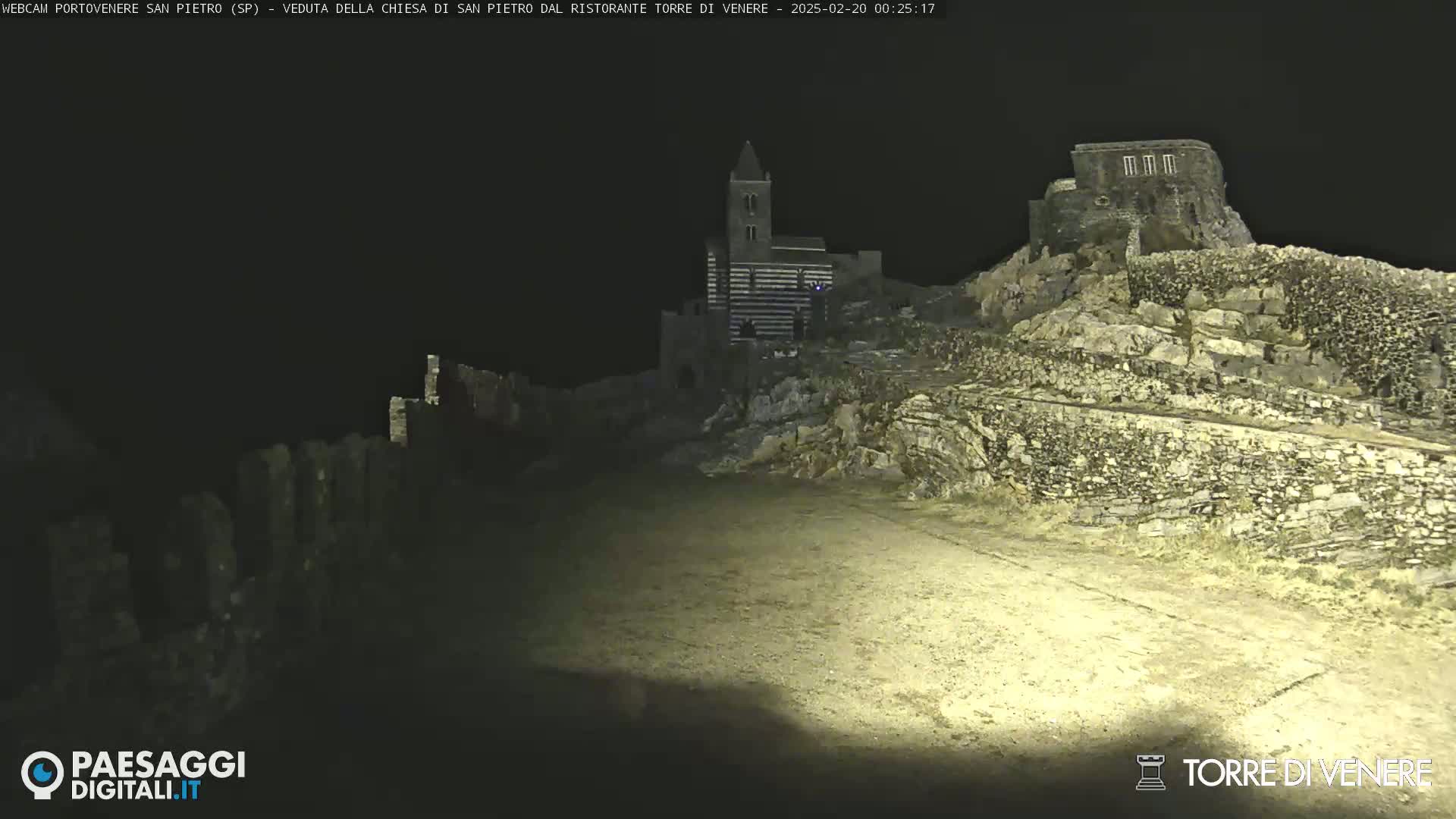 A nighttime view of a stone church and ruins illuminated by artificial light.