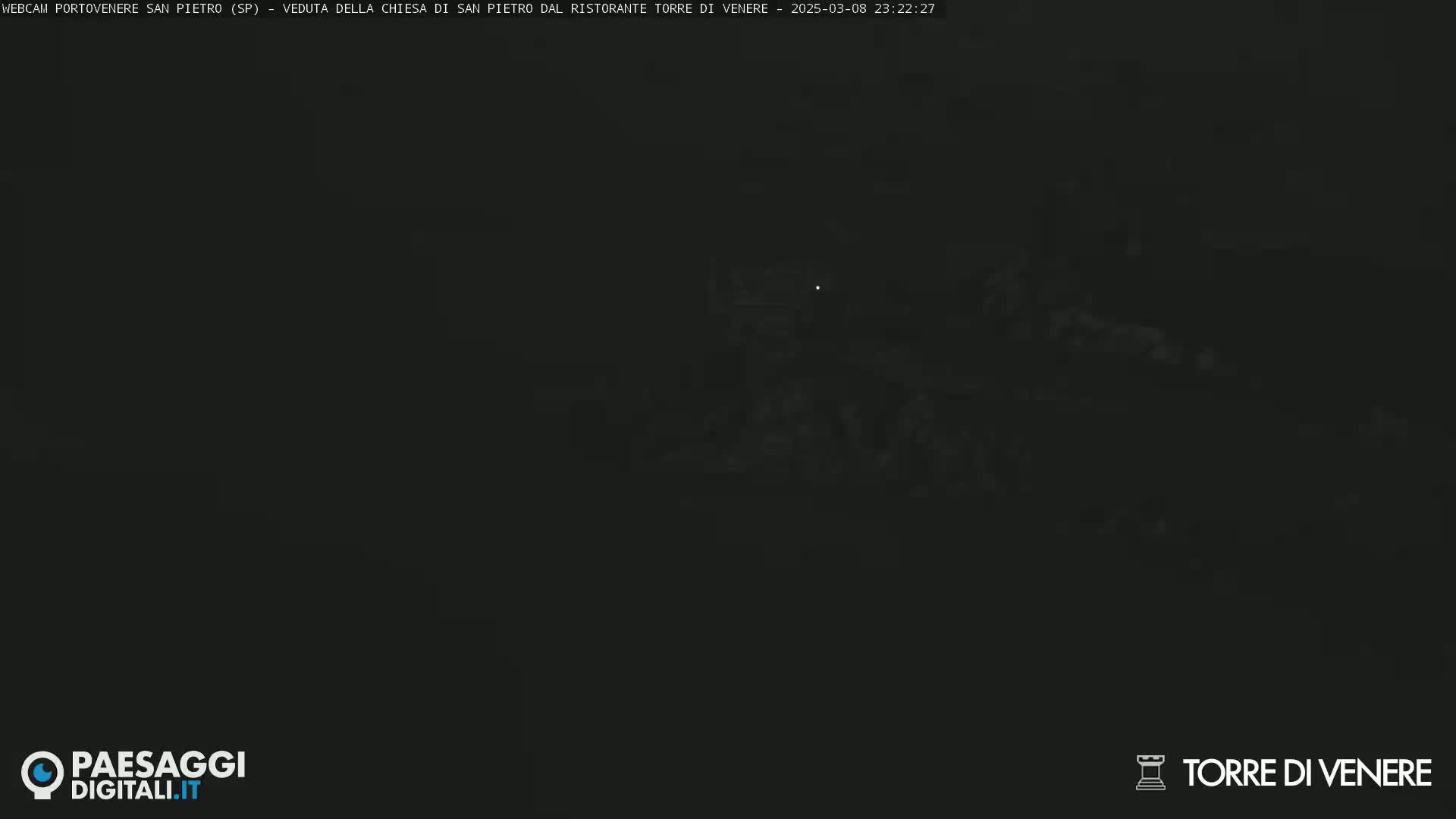A very dark, nighttime image shows a dimly lit structure in the distance.
