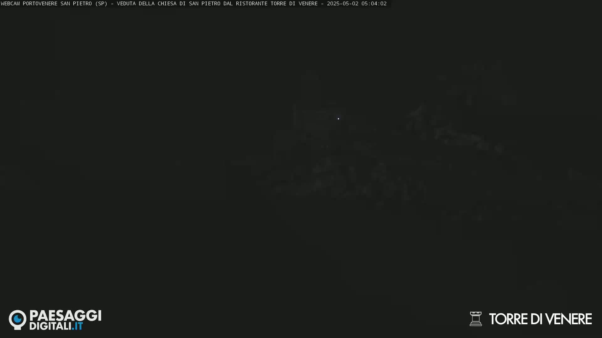 A very dark, nighttime image shows indistinct shapes that appear to be buildings.