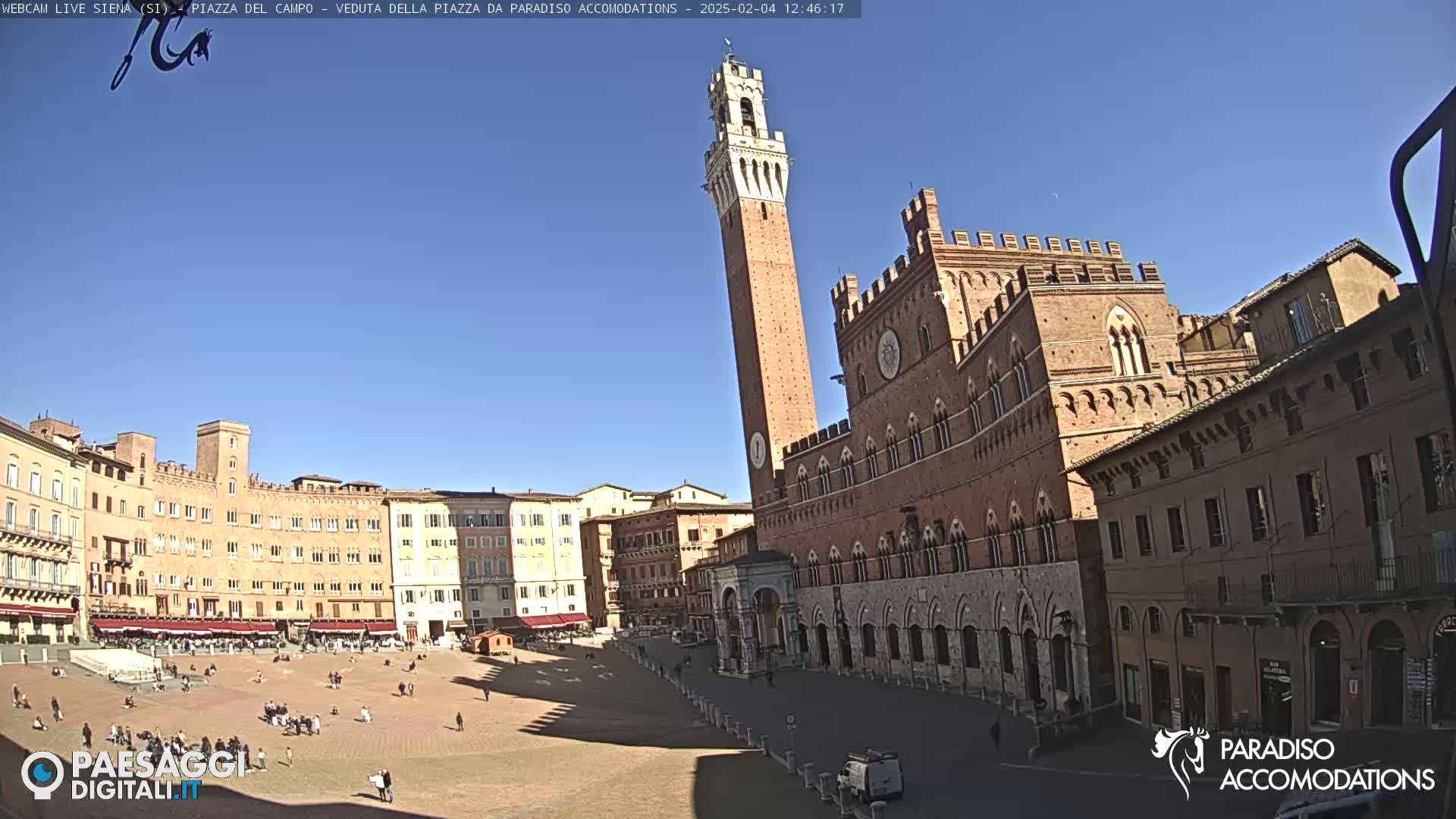 A large, brick public square in Siena, Italy, is shown on a sunny day, with the Palazzo Pubblico and Torre del Mangia prominently featured.