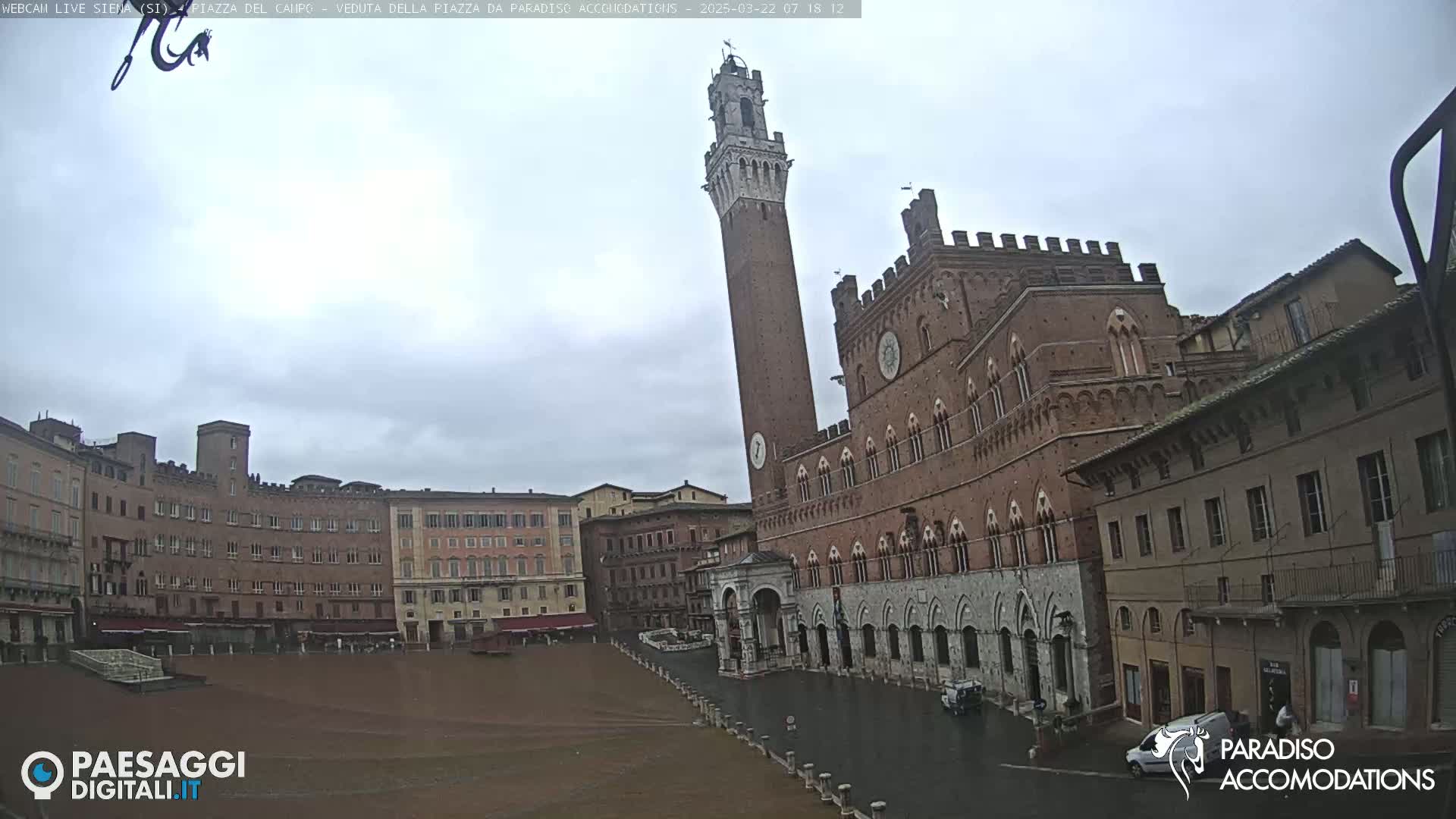 A large, brick piazza in Siena, Italy, is shown on an overcast day.