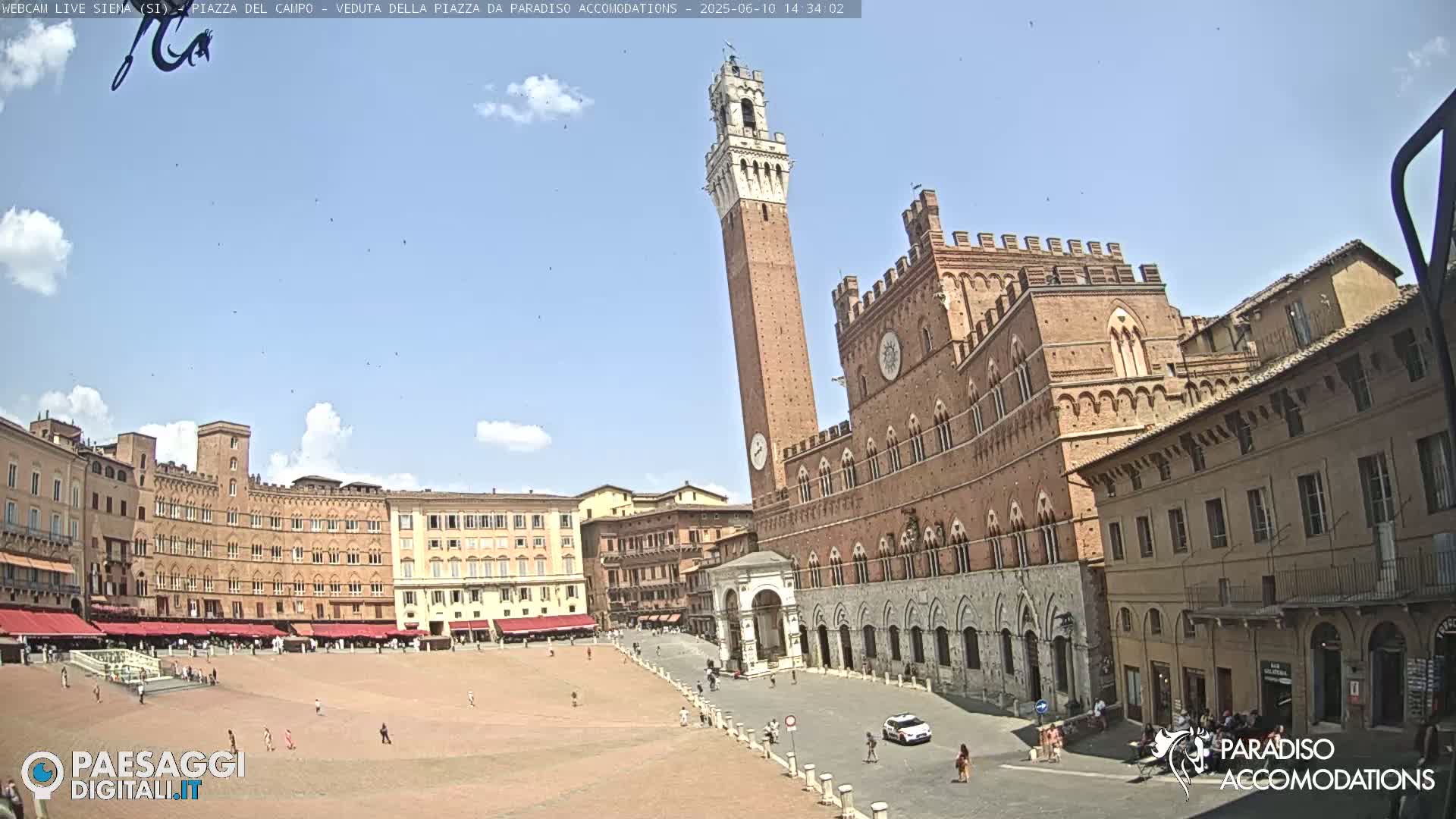 A large, mostly empty plaza in Siena, Italy, is surrounded by brick buildings under a partly cloudy sky.