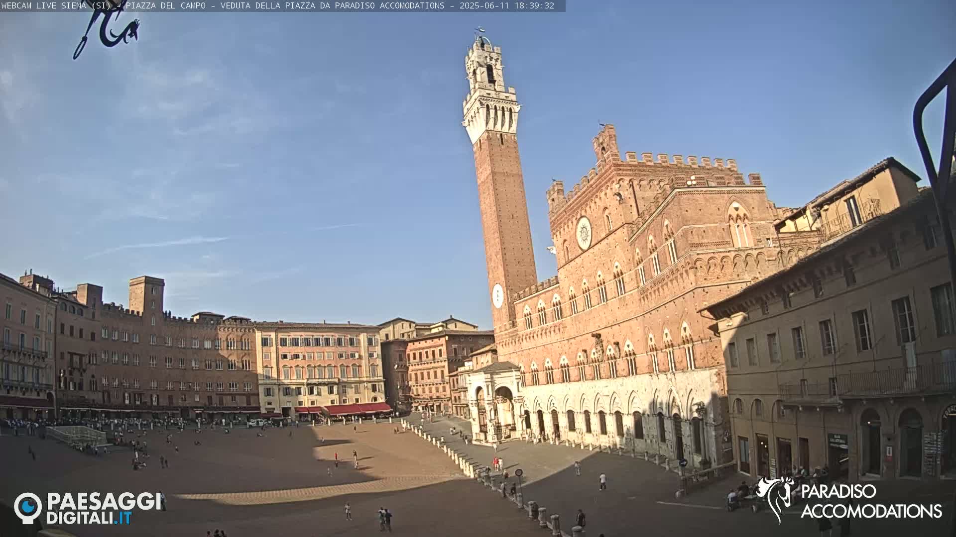 A large, mostly empty, brick plaza is surrounded by historical buildings under a clear blue sky.