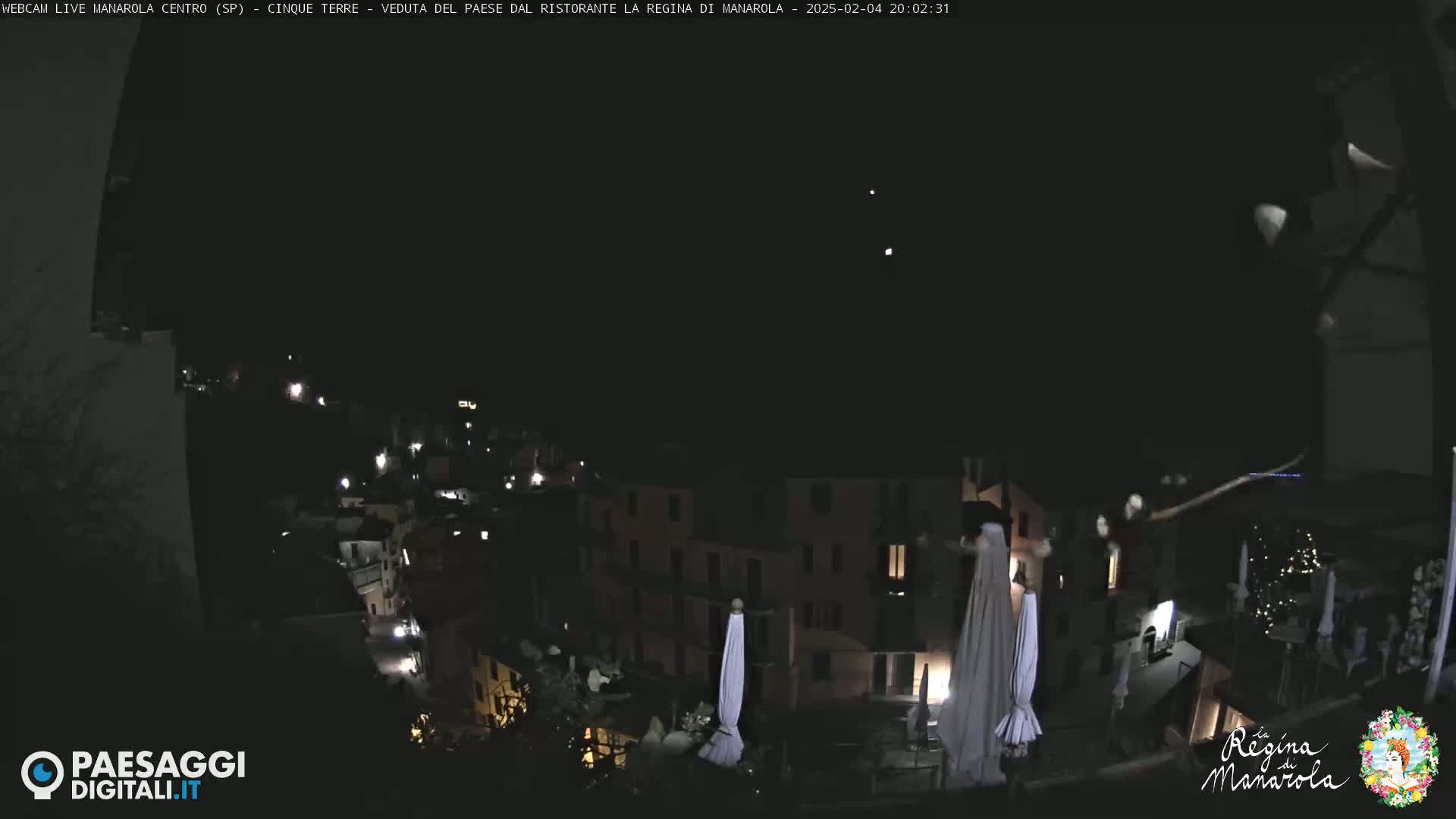 A nighttime view of a village nestled on a hillside, under a clear, dark sky.