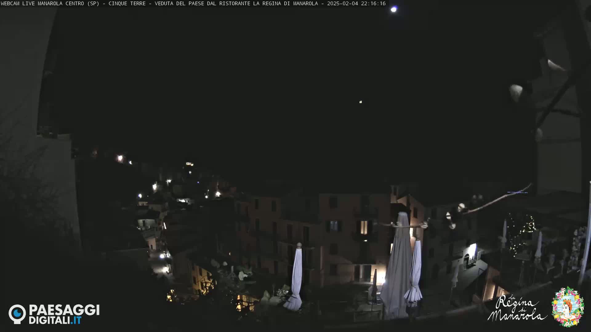 A nighttime view of a village, illuminated by scattered lights under a clear, dark sky.