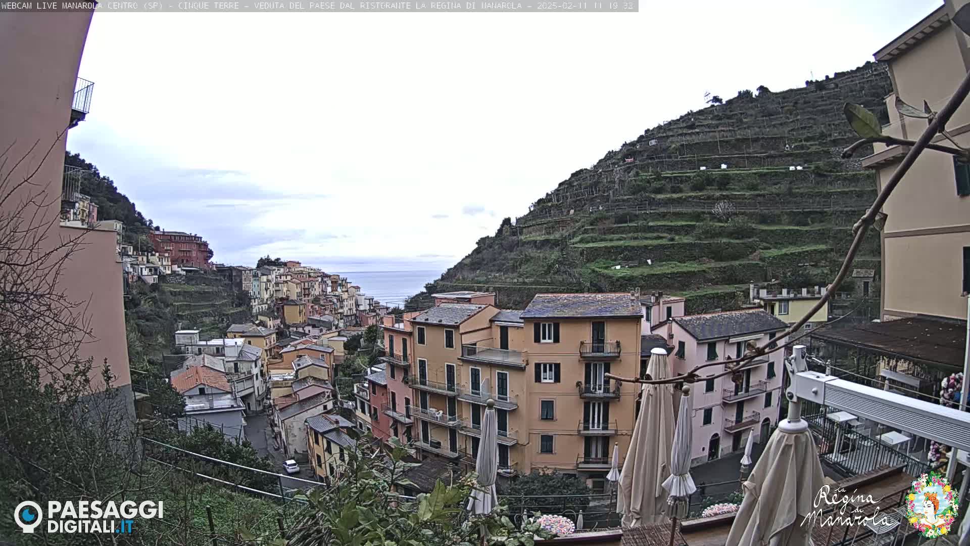 A coastal village with colorful buildings on a hillside overlooking the sea under an overcast sky.