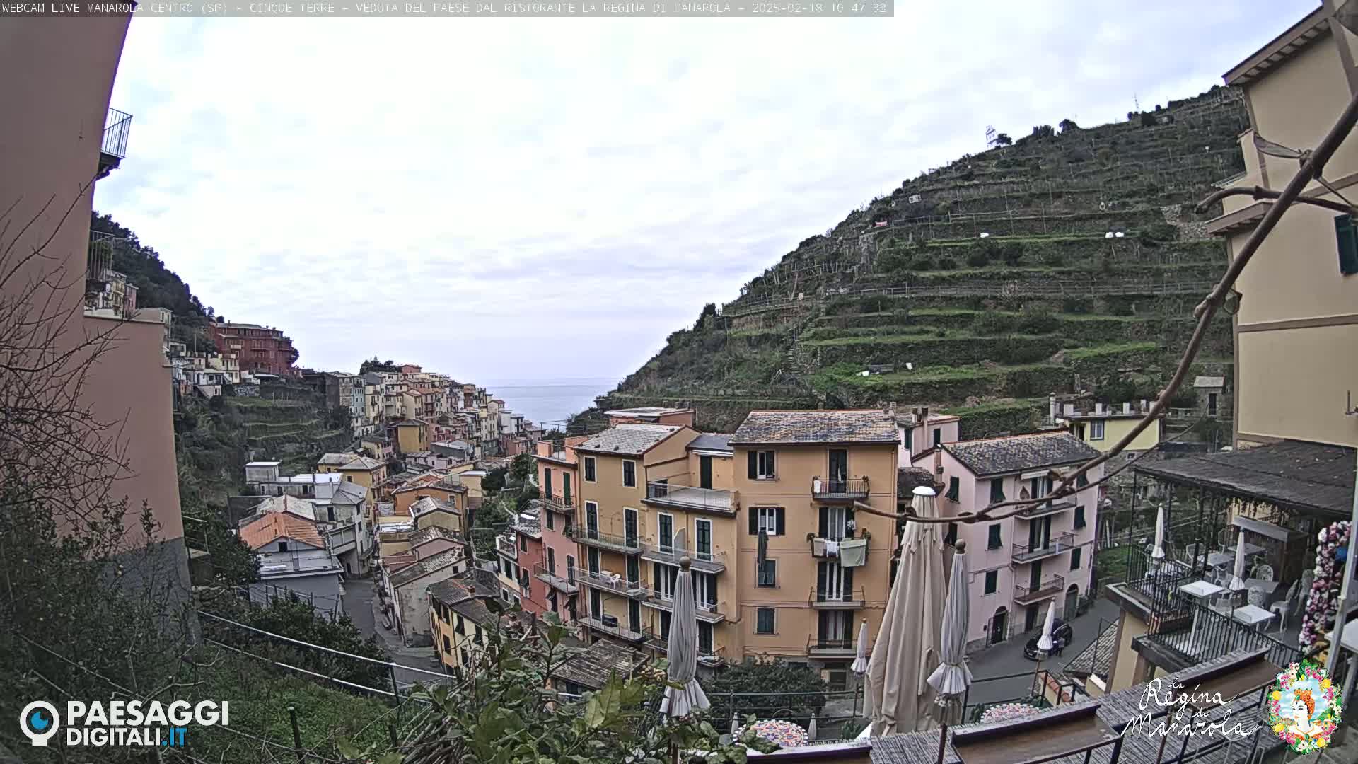 A view of a colorful hillside town overlooking the sea on a cloudy day.