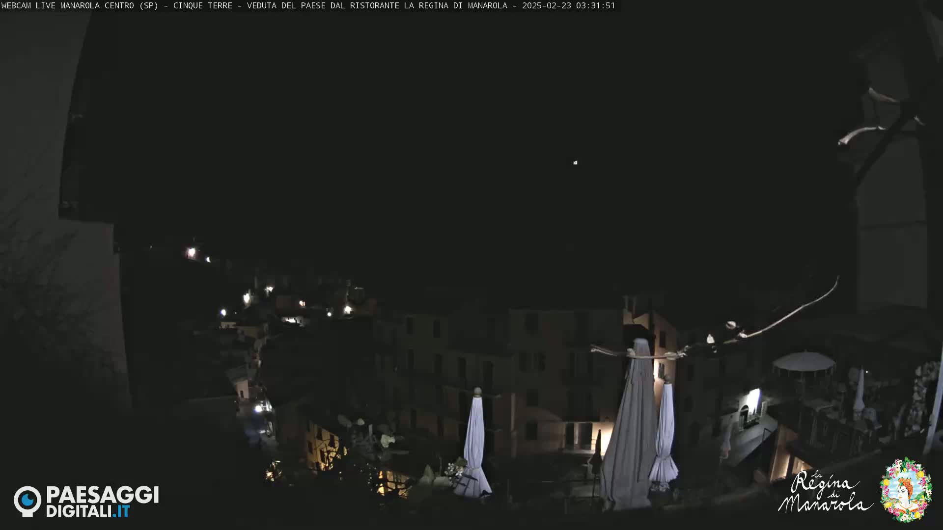 A nighttime, dark view of a town with some lights visible, featuring closed umbrellas and a dark sky.