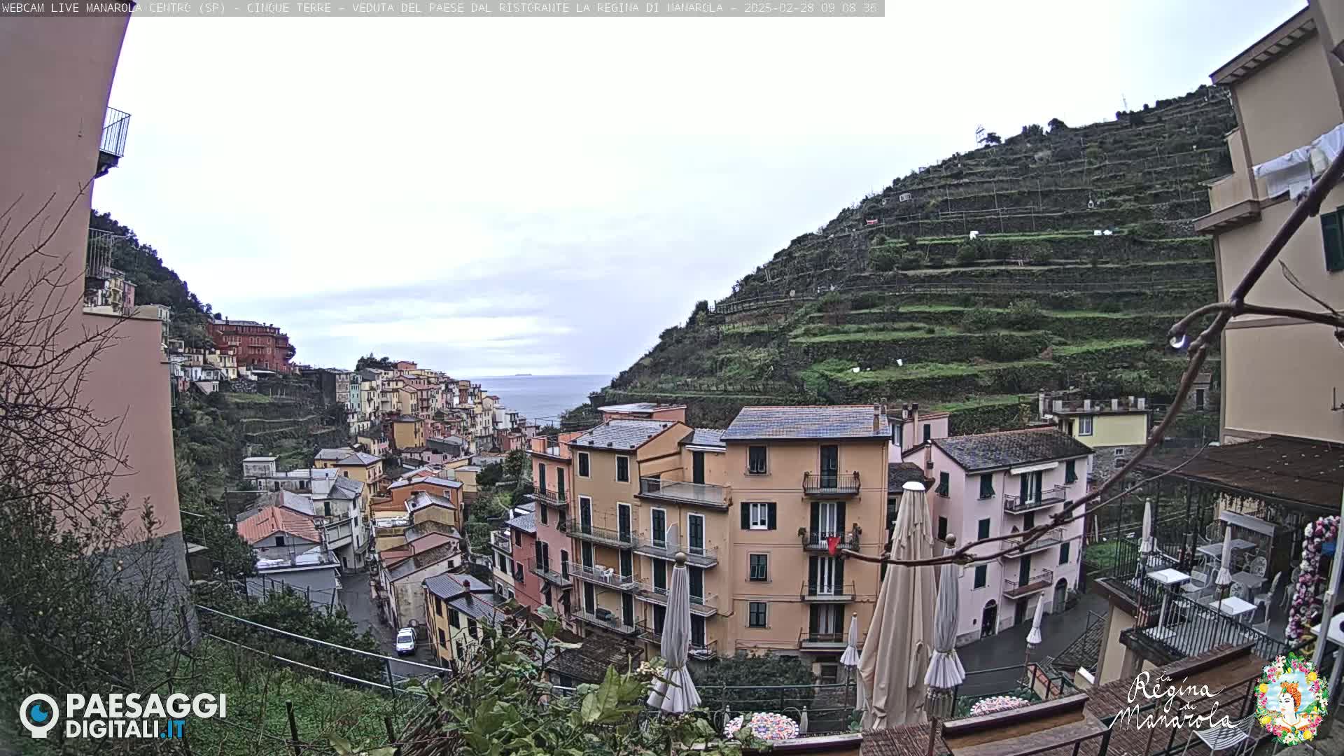 A view of a colorful hillside town overlooking the ocean on an overcast day.