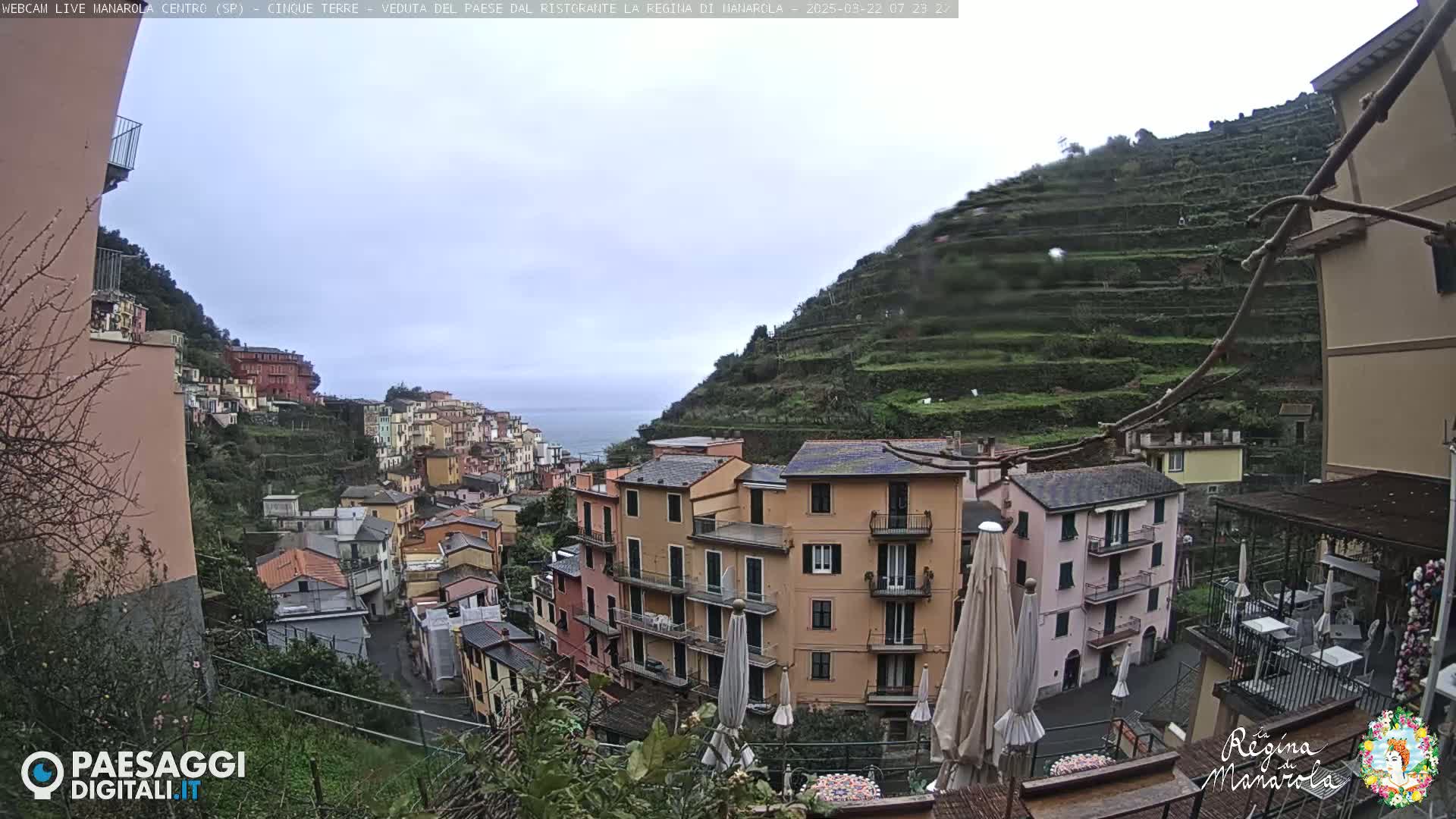 A view of a colorful hillside town overlooking the sea on an overcast day.