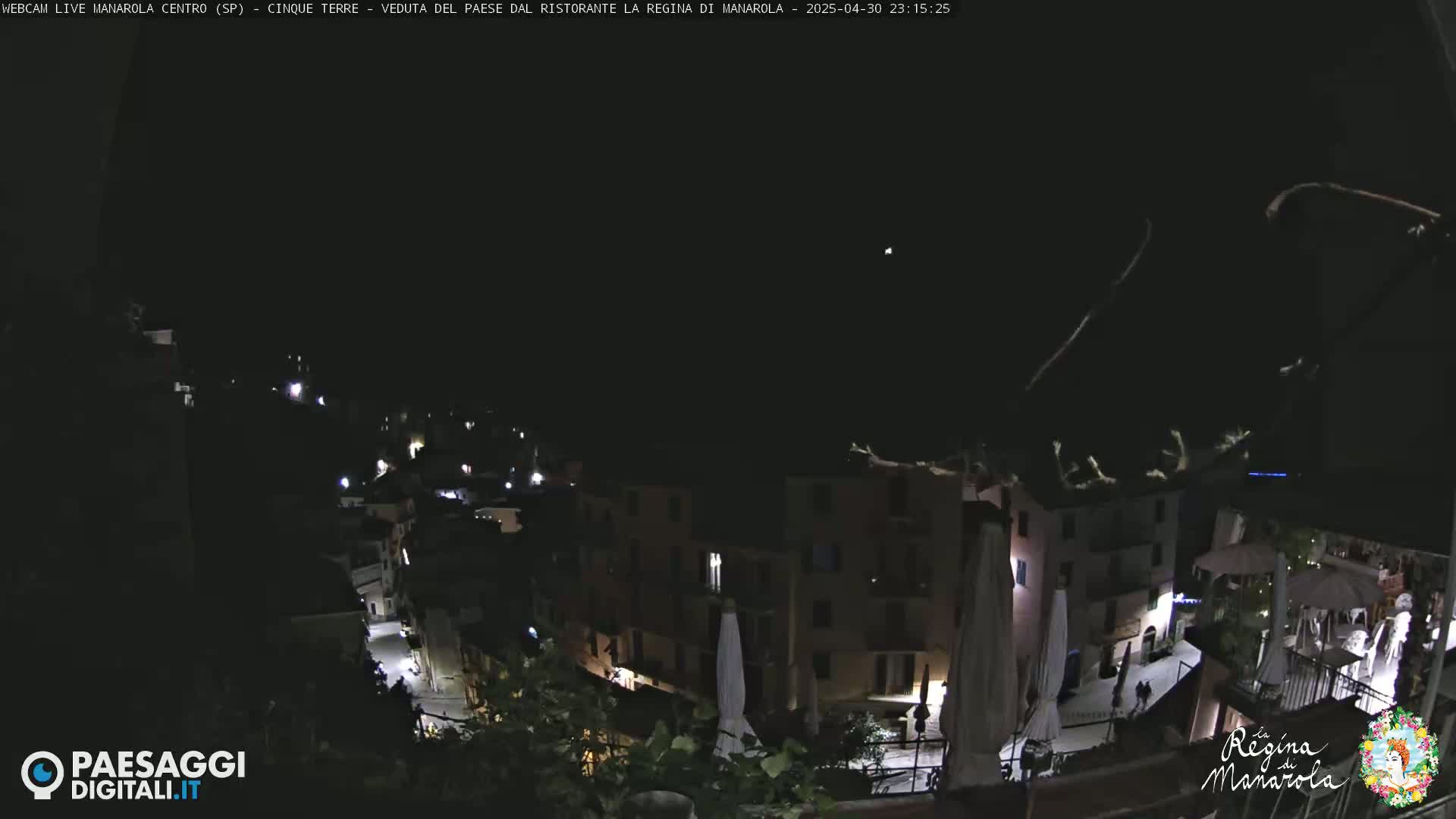 A nighttime view of a village, illuminated by scattered lights, under a clear, dark sky.