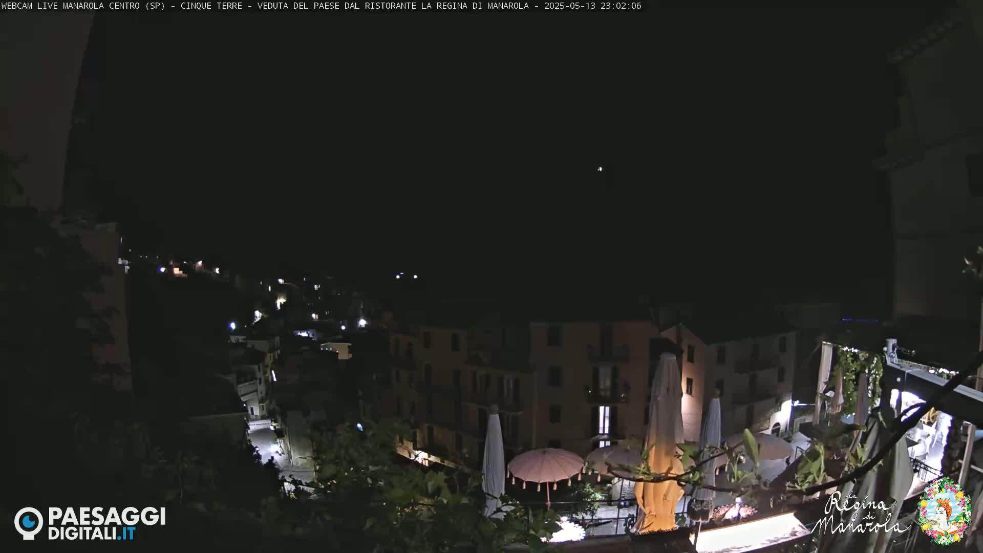 A nighttime view of a village, illuminated by scattered lights, under a clear, dark sky.