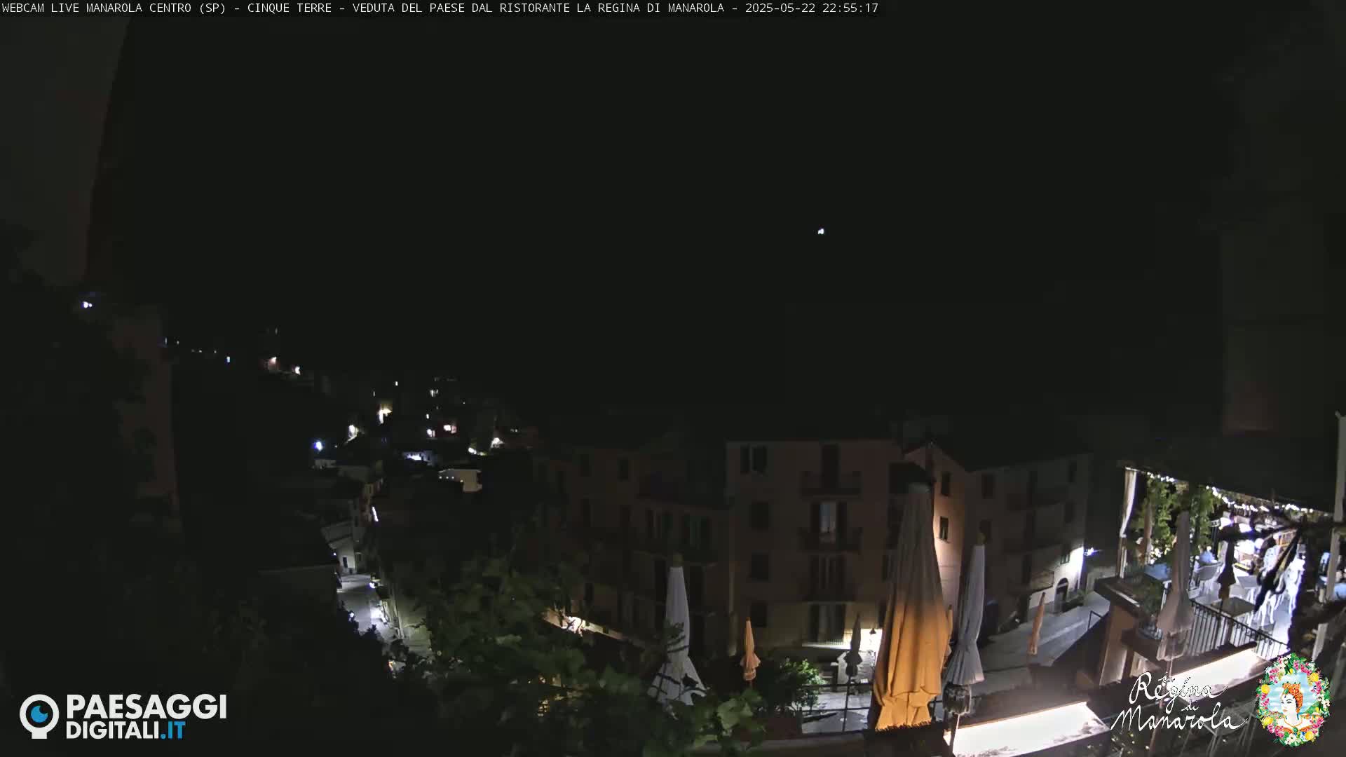 A nighttime, clear-sky view of a town situated on a hillside, with some lights visible from buildings and streets.
